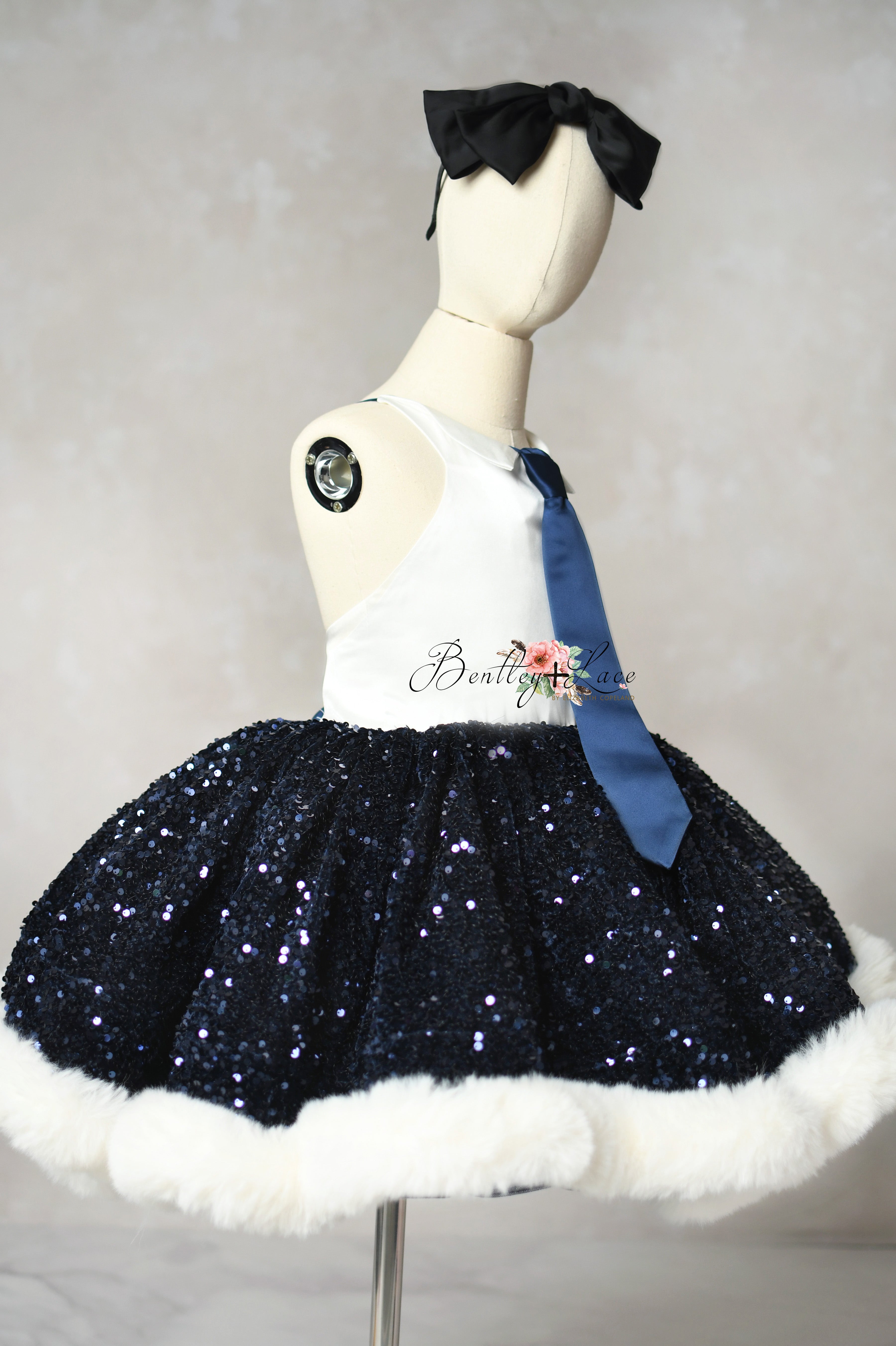 Mannequin wearing a navy sequin skirt with white trim and a blue sash on a plain background.