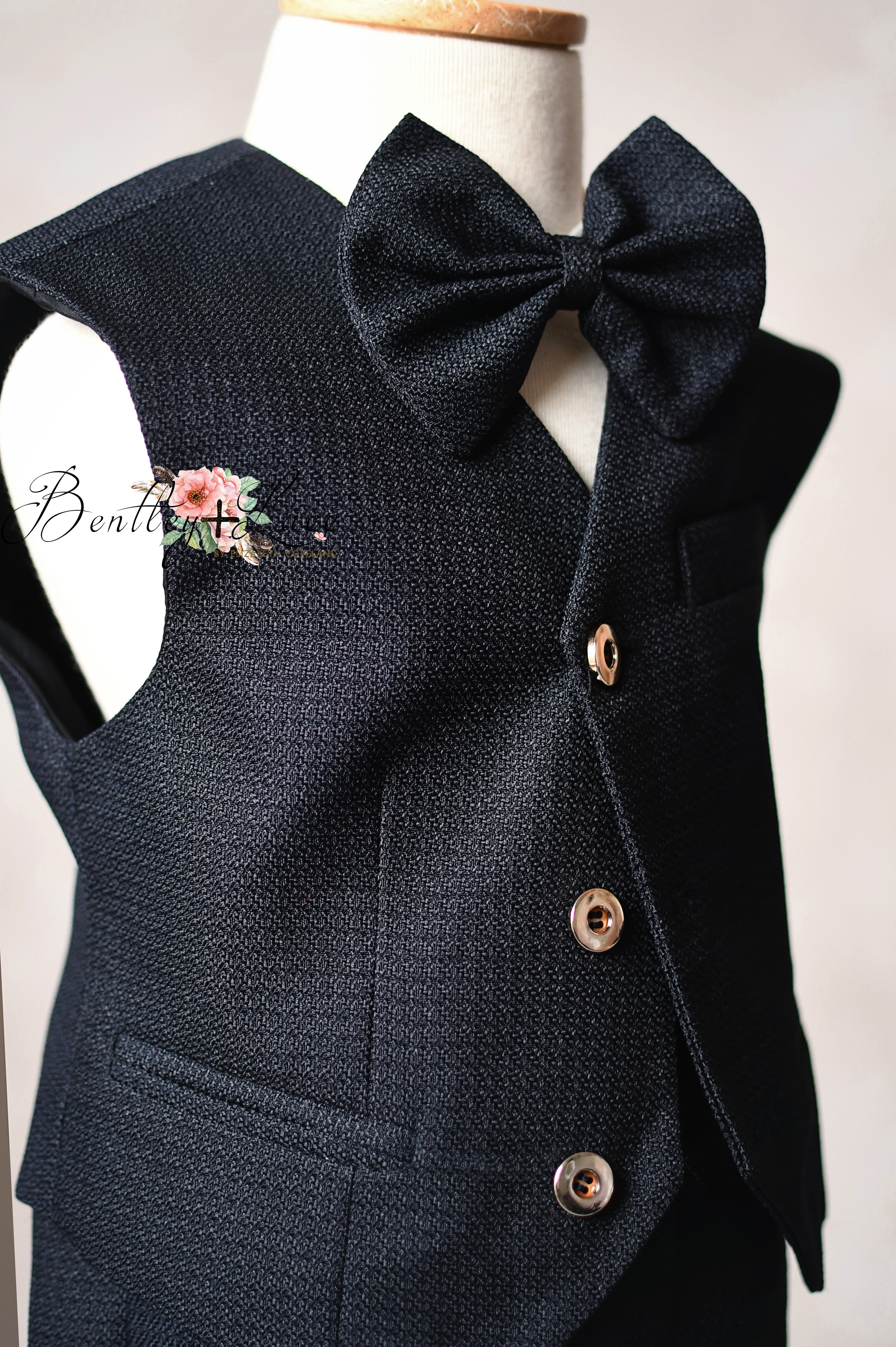 Black vest with a large bow tie on a mannequin against a white background