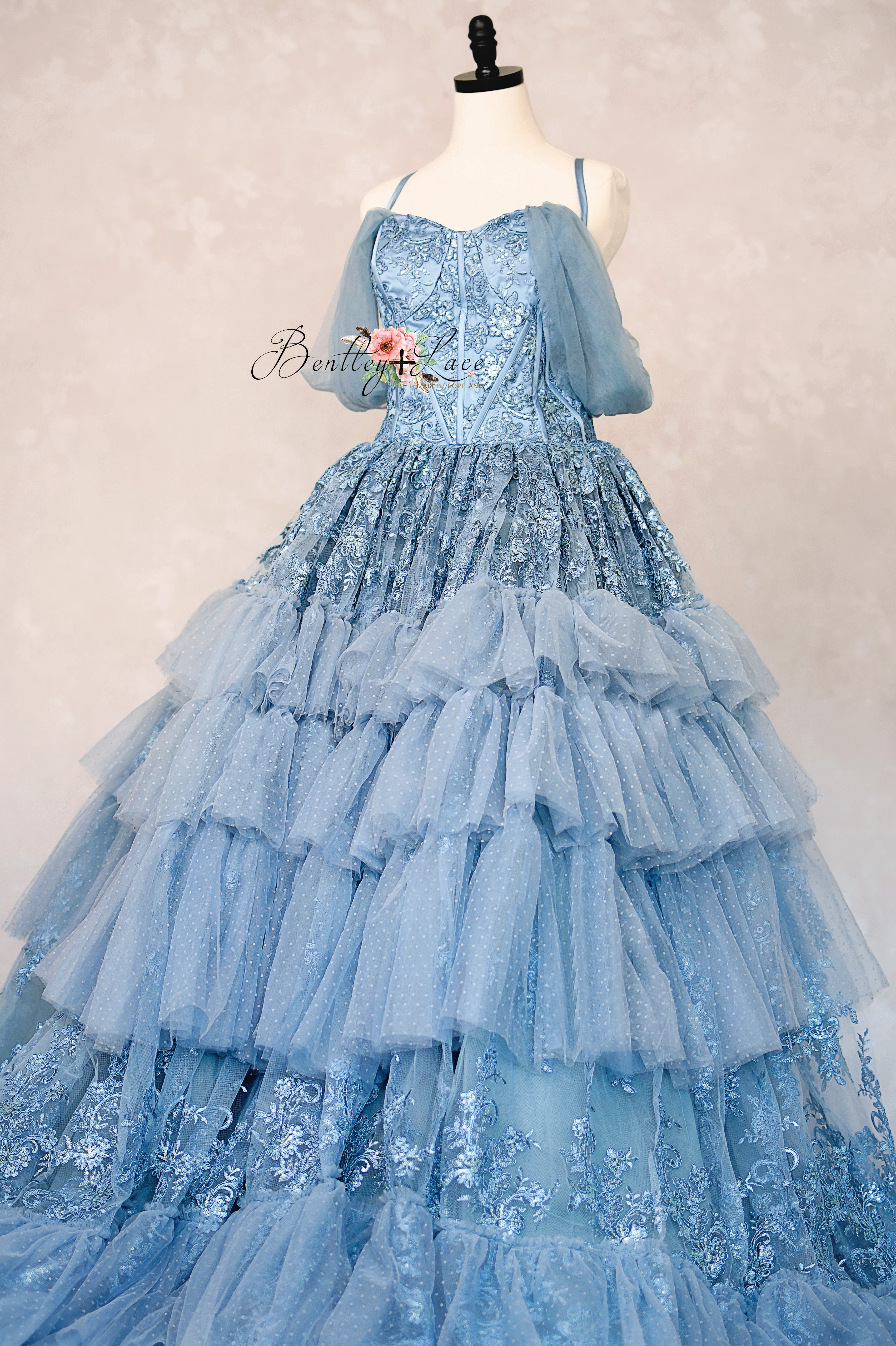 Blue ball gown on a mannequin against a plain background