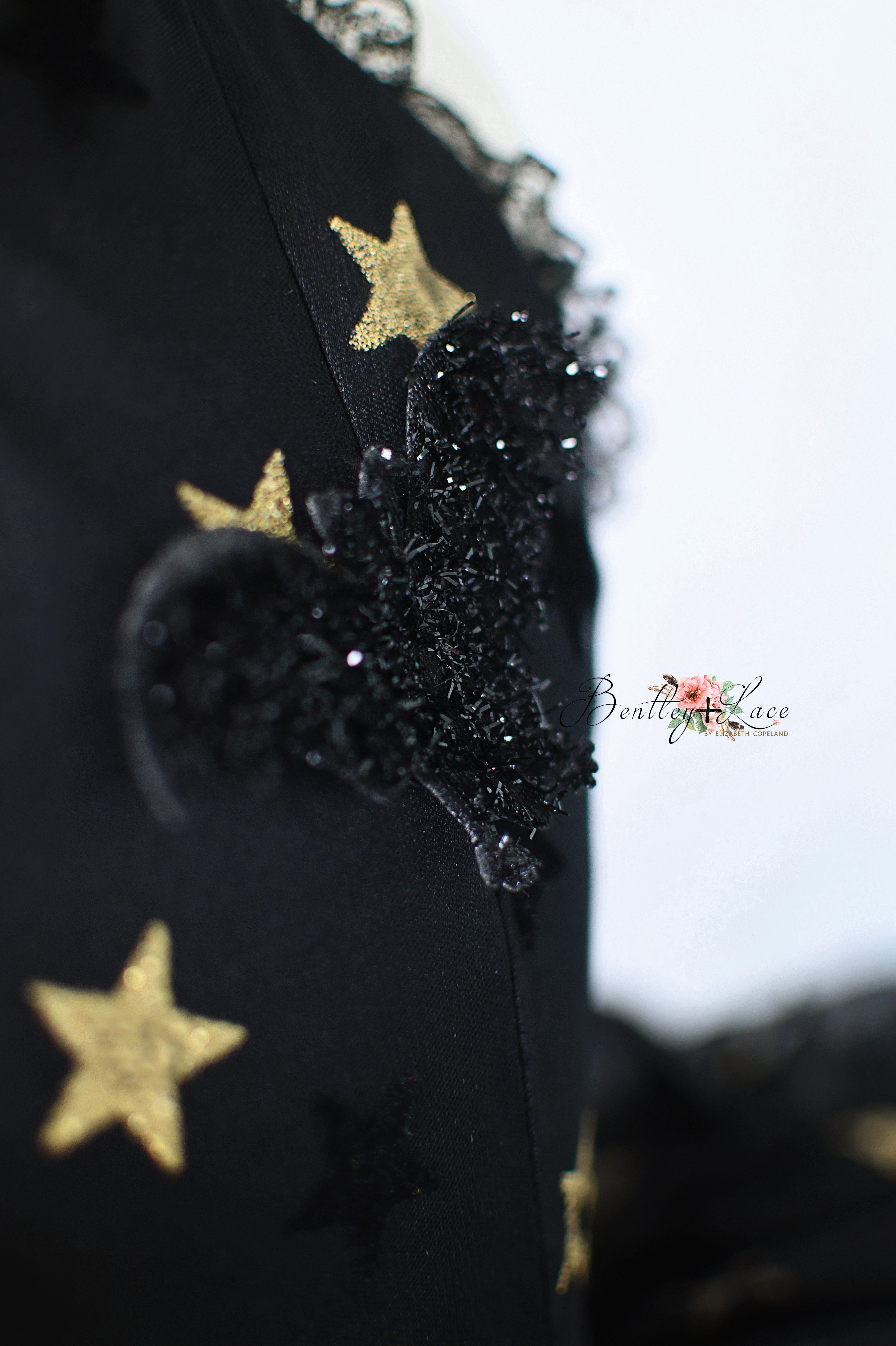 Black garment with gold stars and decorative elements on a blurred background
