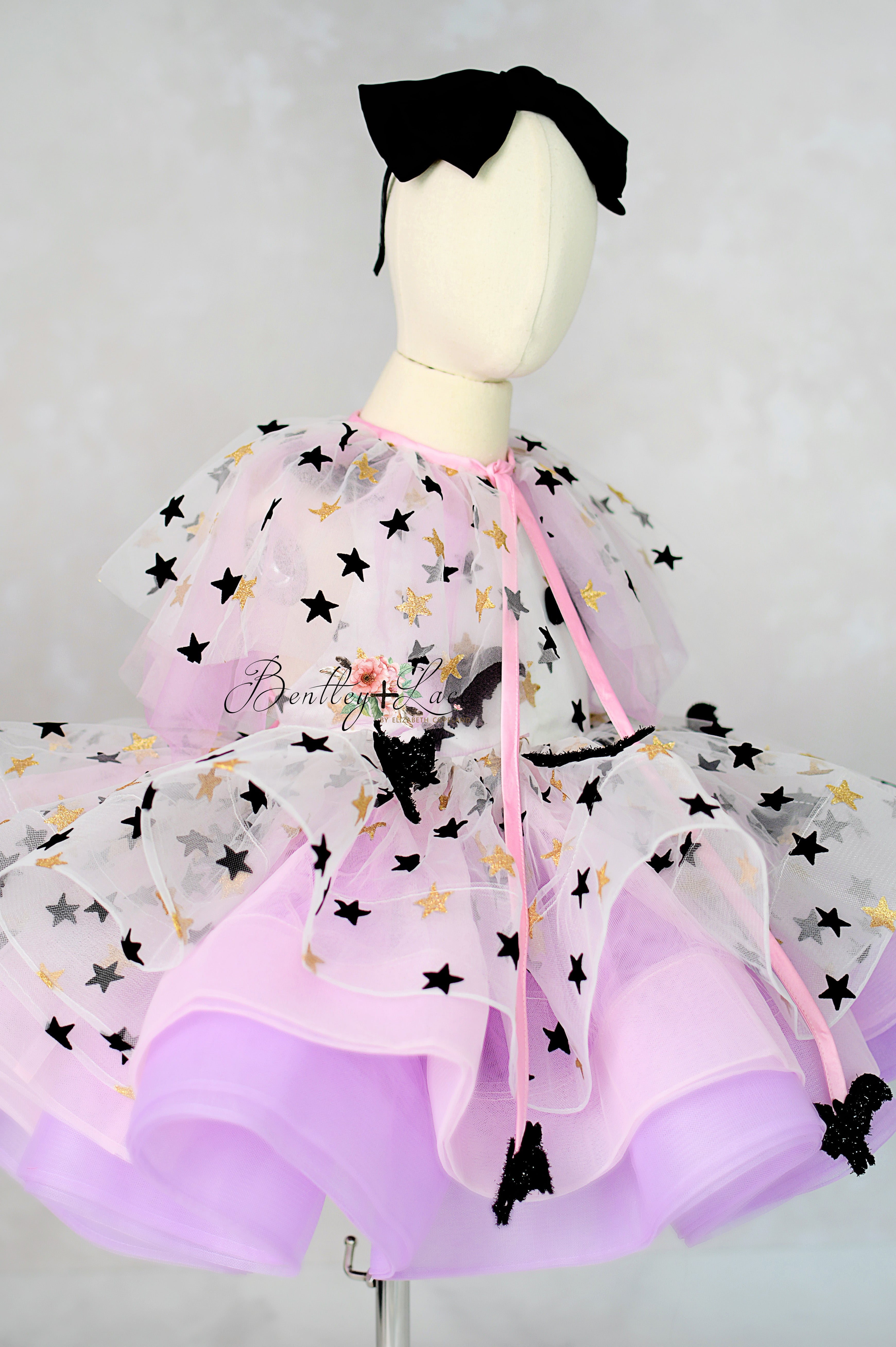 Mannequin wearing a purple dress with black star patterns on a white background