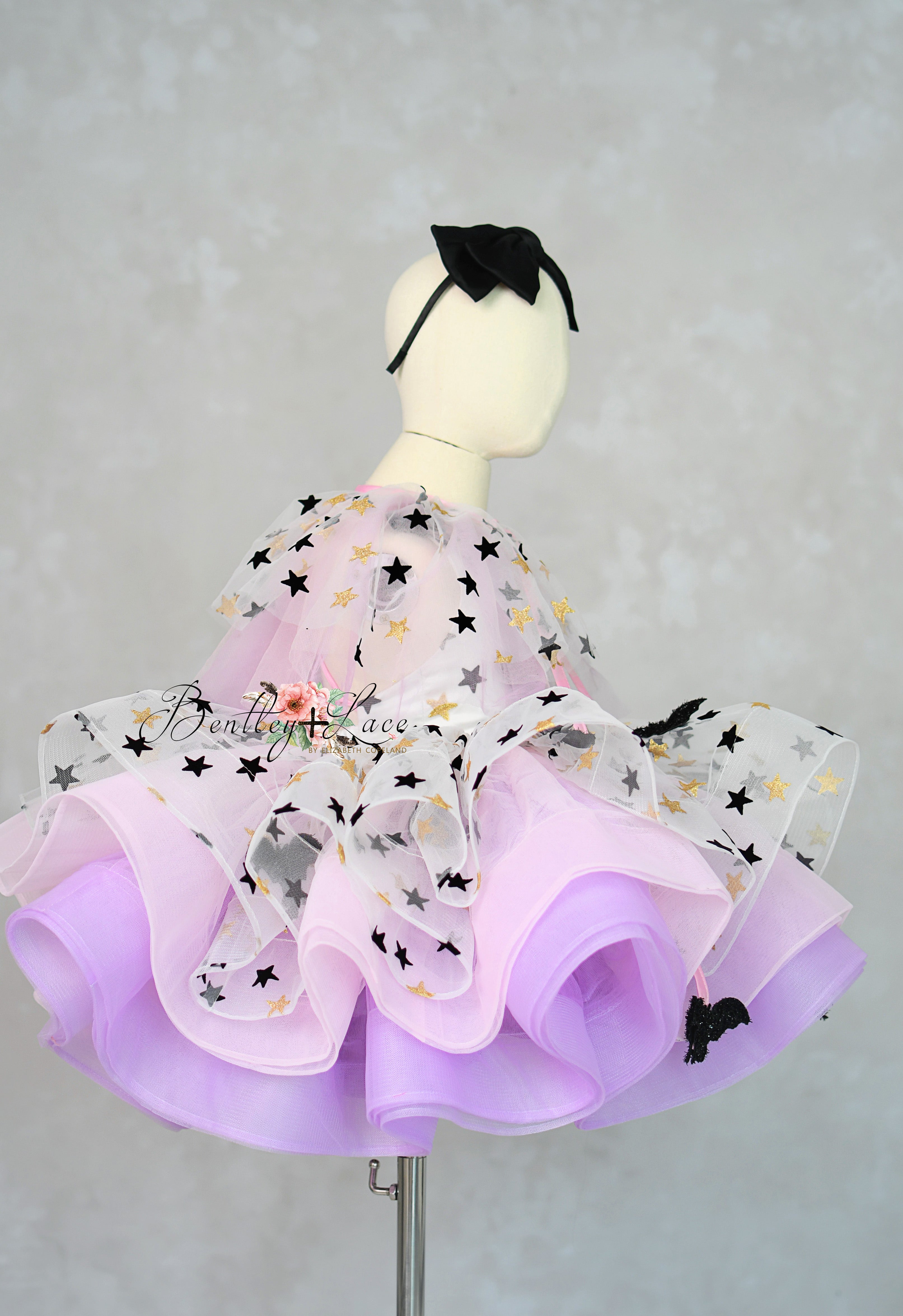 Mannequin wearing a purple dress with star patterns on a gray background