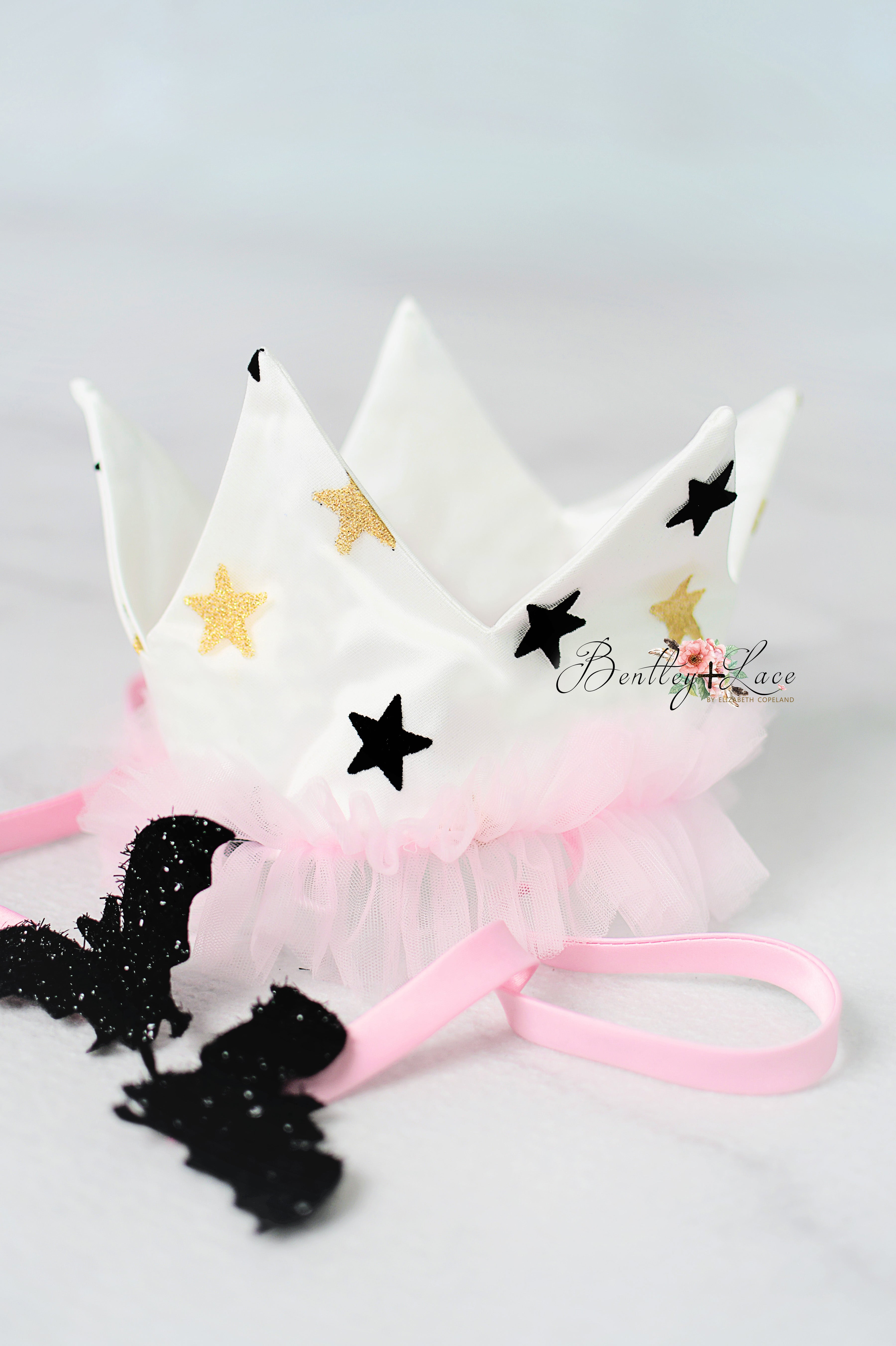 White crown with black and gold stars on a white background