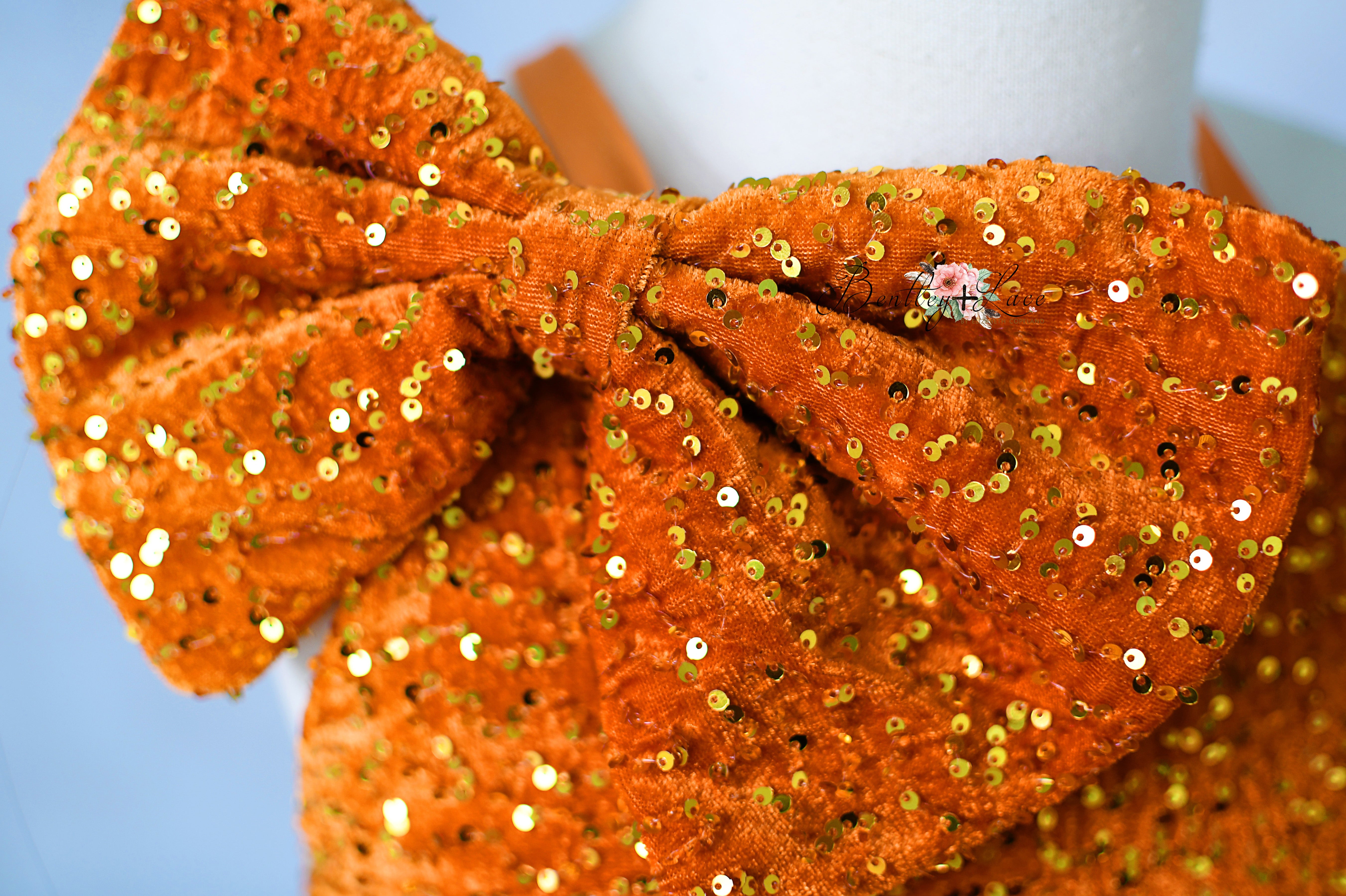 Orange sequin headband on a light blue background