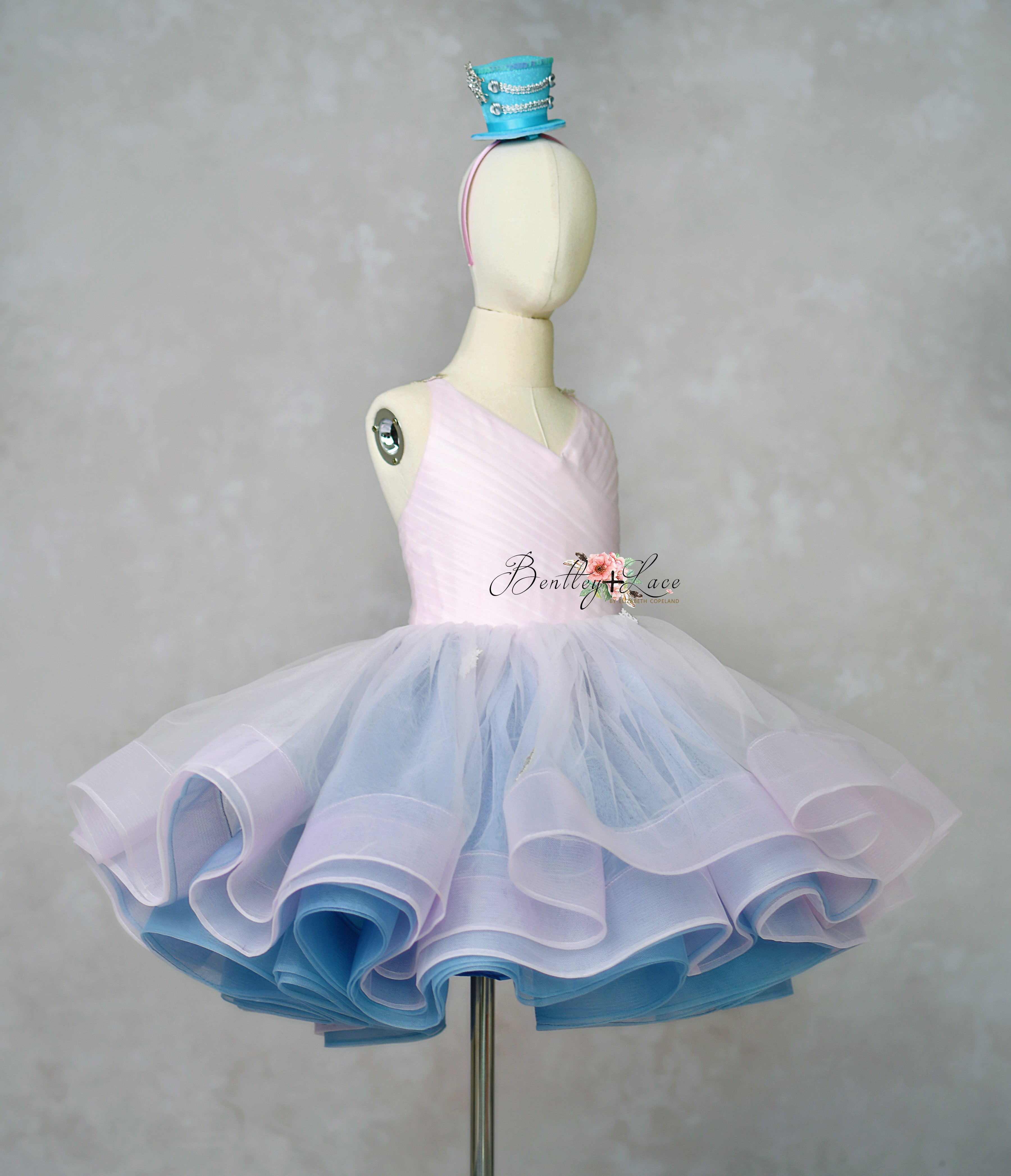 Mannequin wearing a two-tone pink and blue dress with a headband on a plain background.