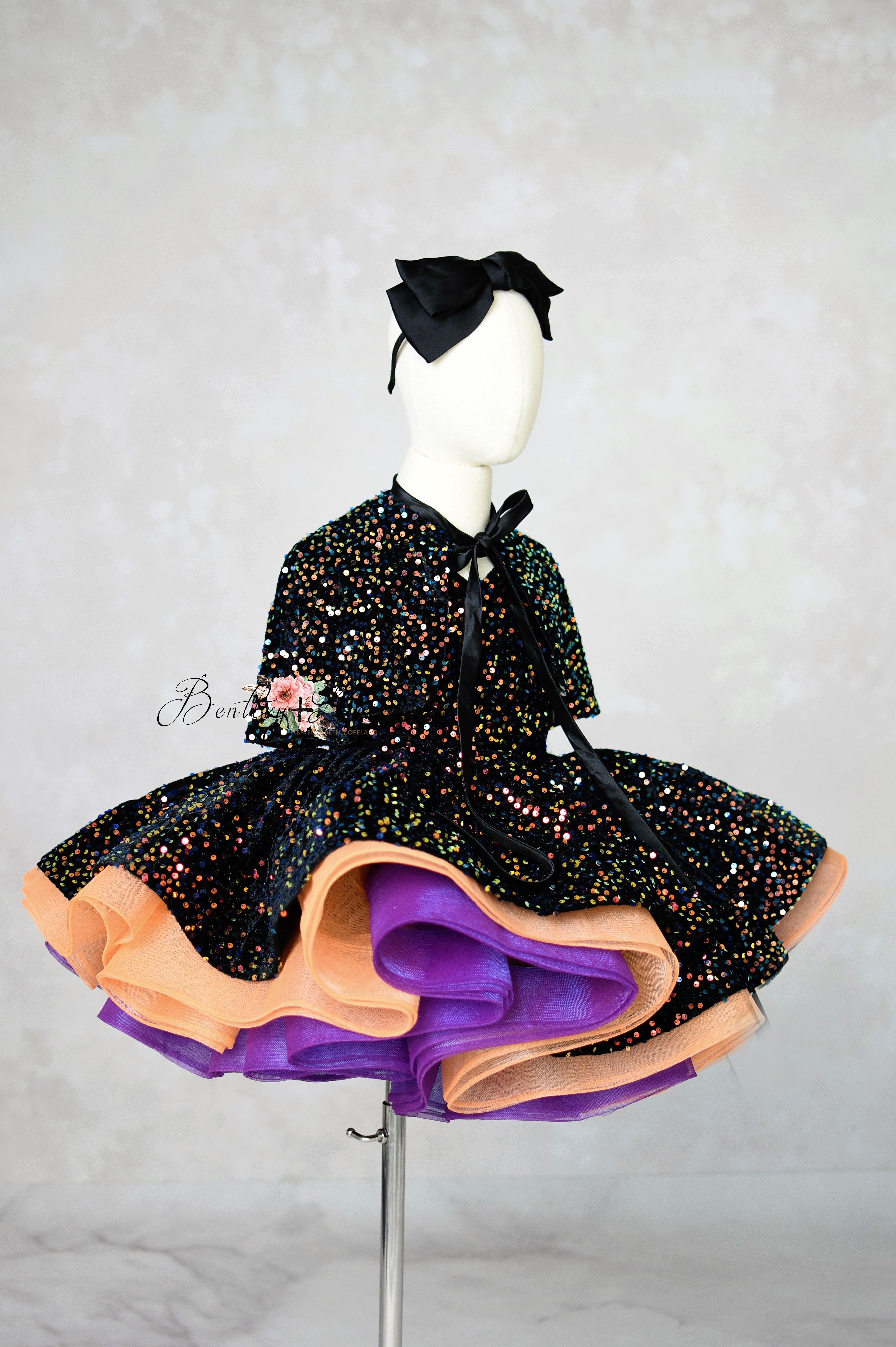 Black dress with colorful skirt on a mannequin against a gray background