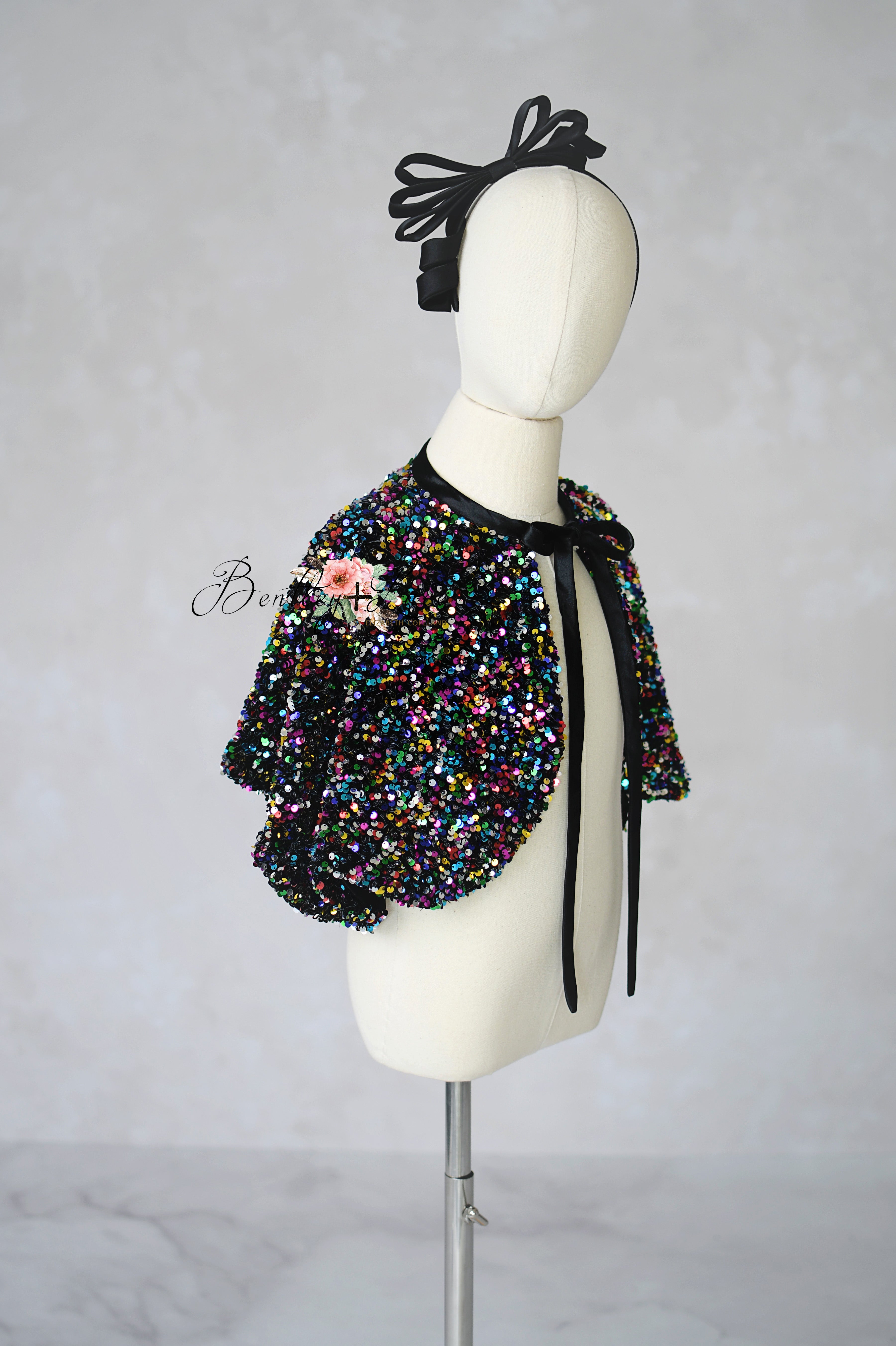 Multicolored beaded jacket on a mannequin with a black headpiece against a plain background