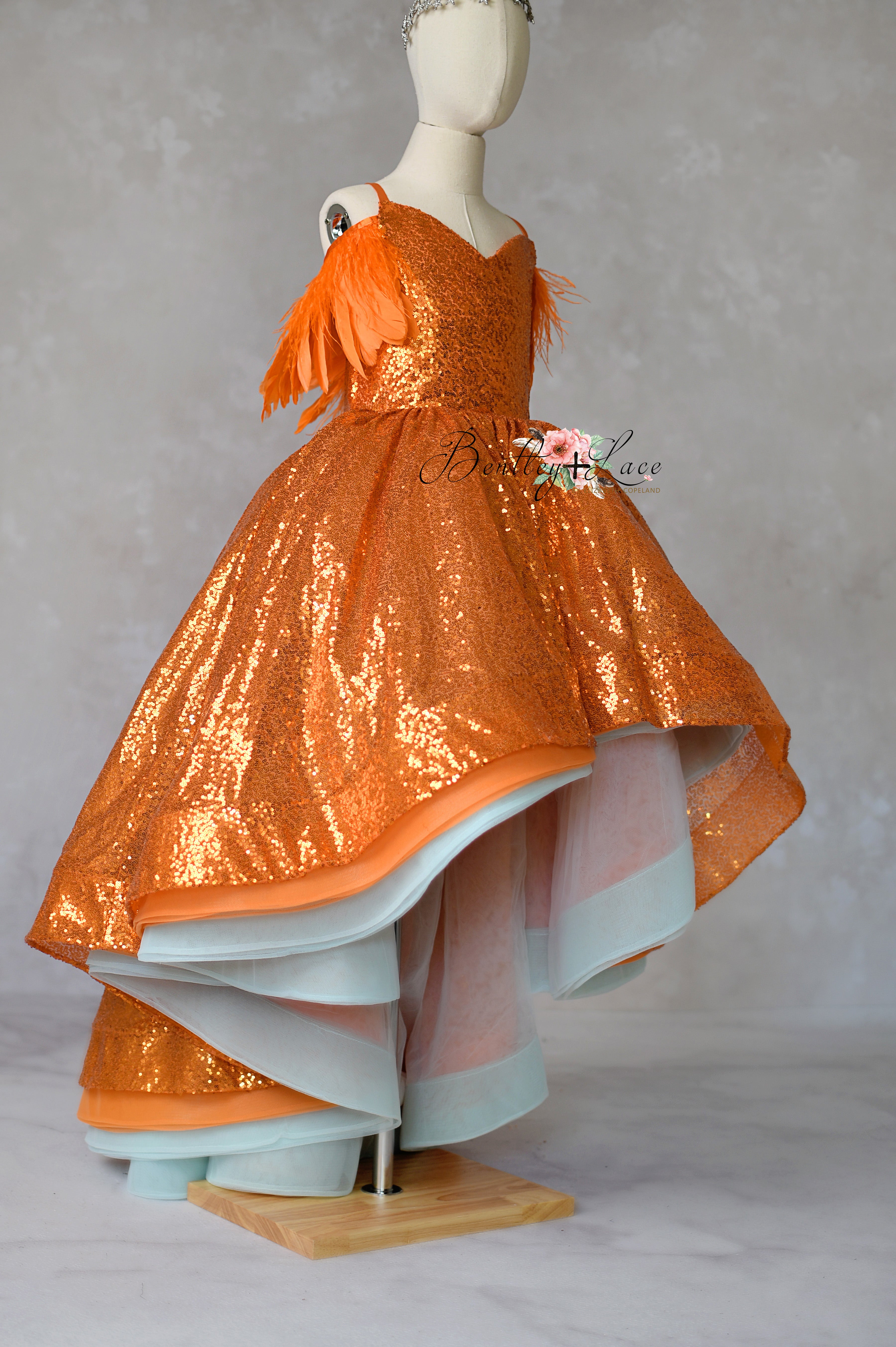 Orange sequin dress on a mannequin against a gray background