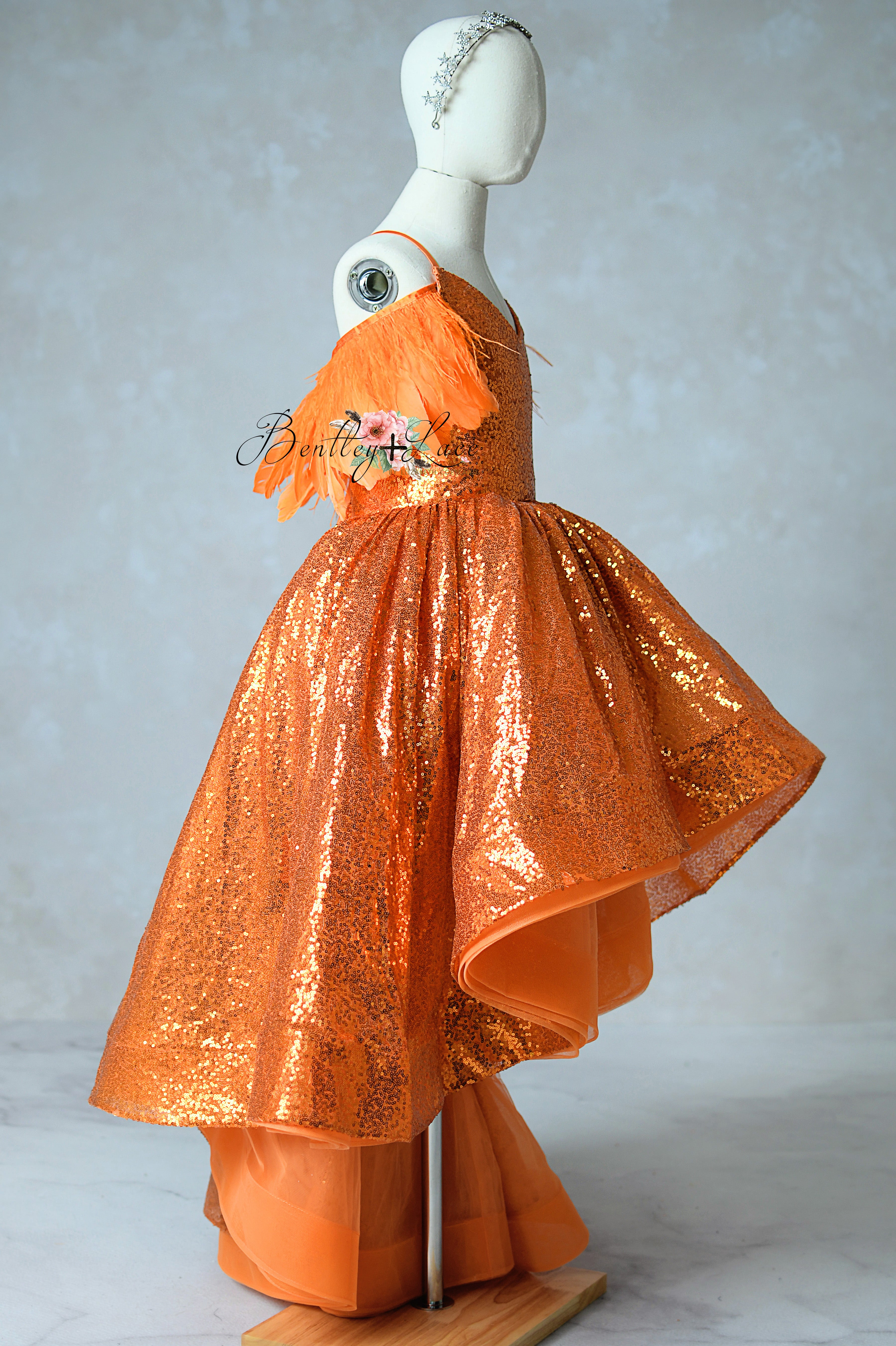 Orange sequined dress on a mannequin against a plain background