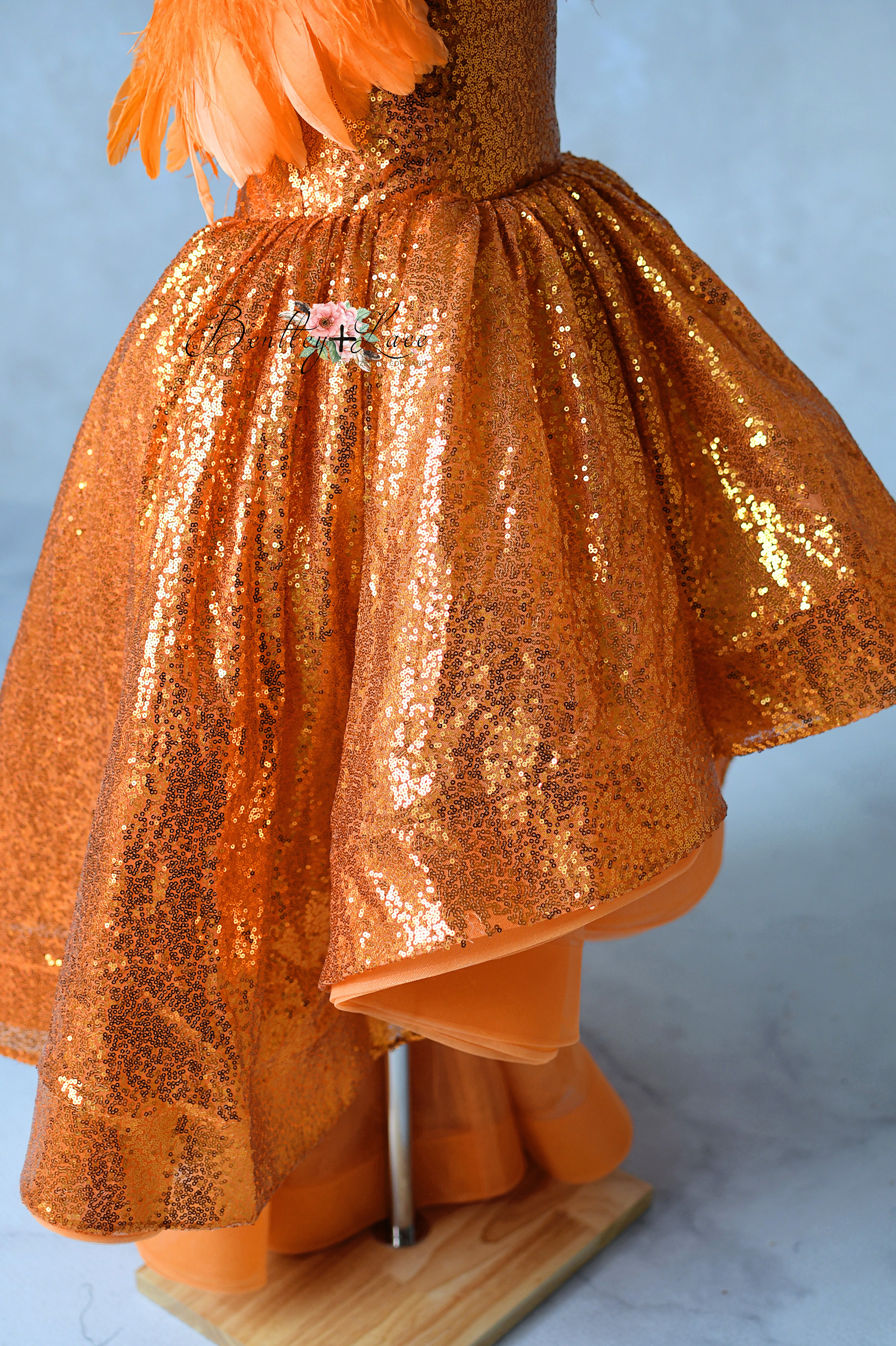 Orange sequin dress on a mannequin against a light blue background