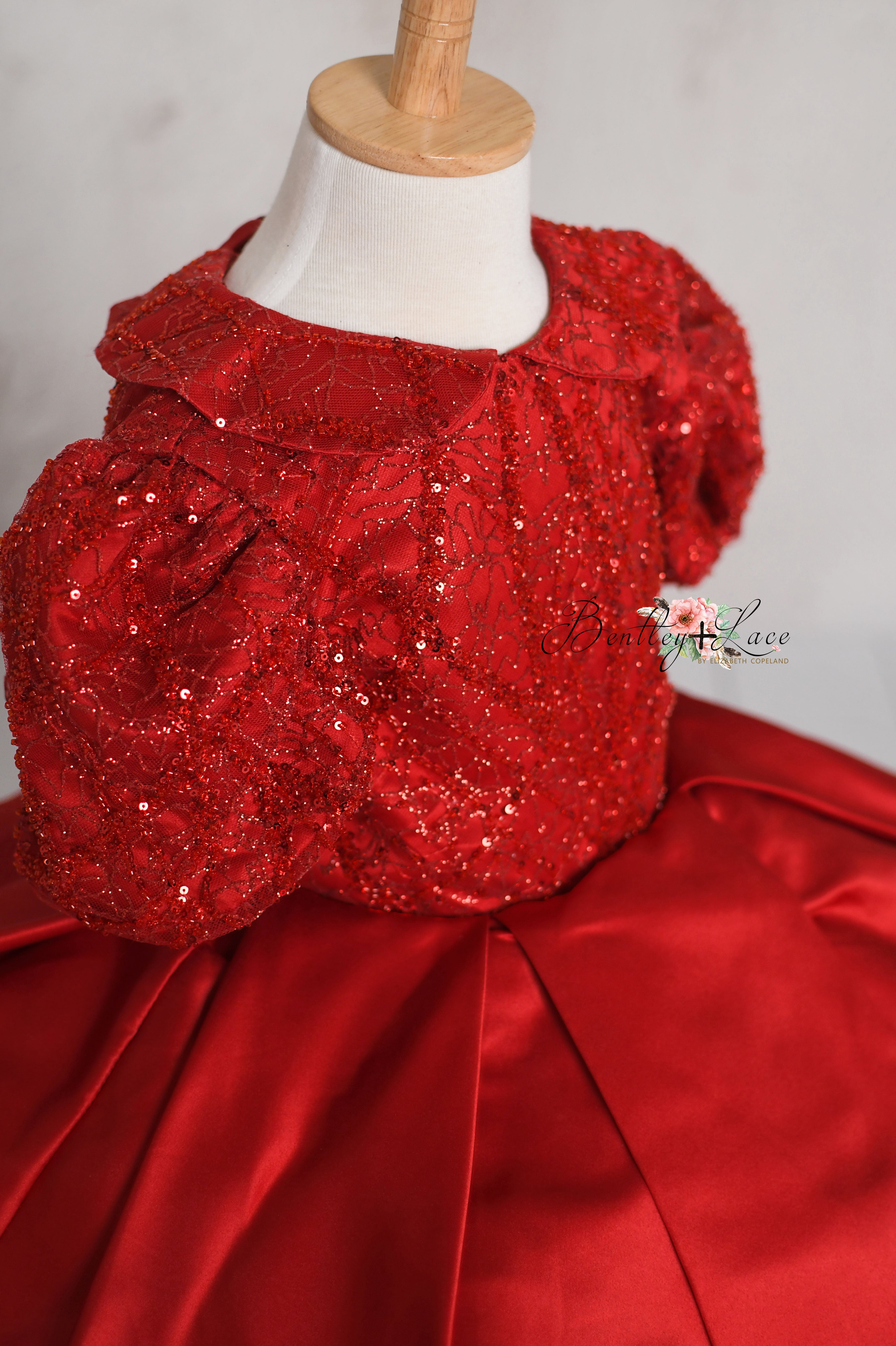 Close-up of the bodice showing intricate sequin embroidery and detailed stitching on a luxurious red gown for young girls.
