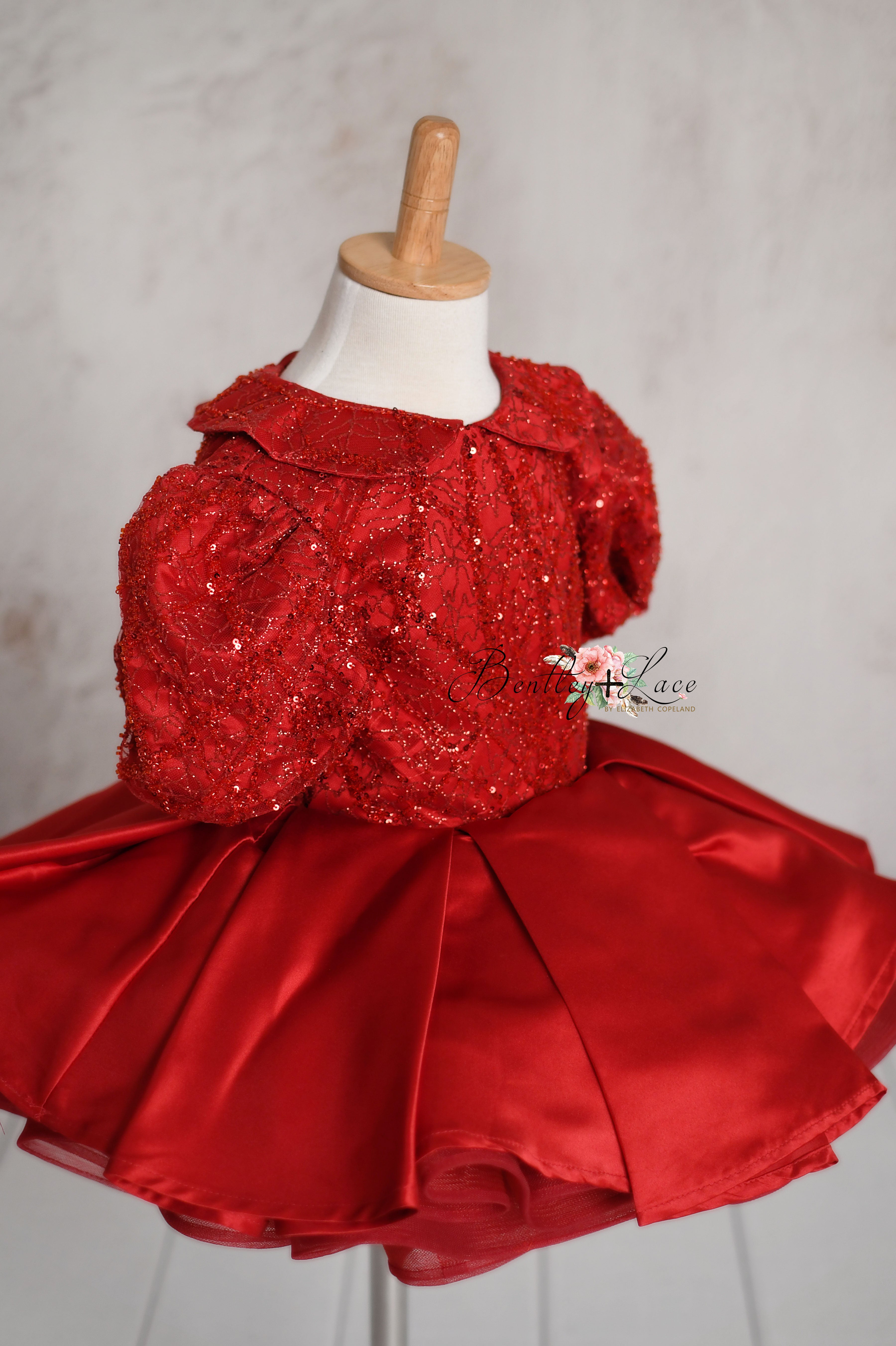 Side profile of a full, pleated satin skirt of the Scarlet Sparkle gown, highlighting its voluminous and elegant design.