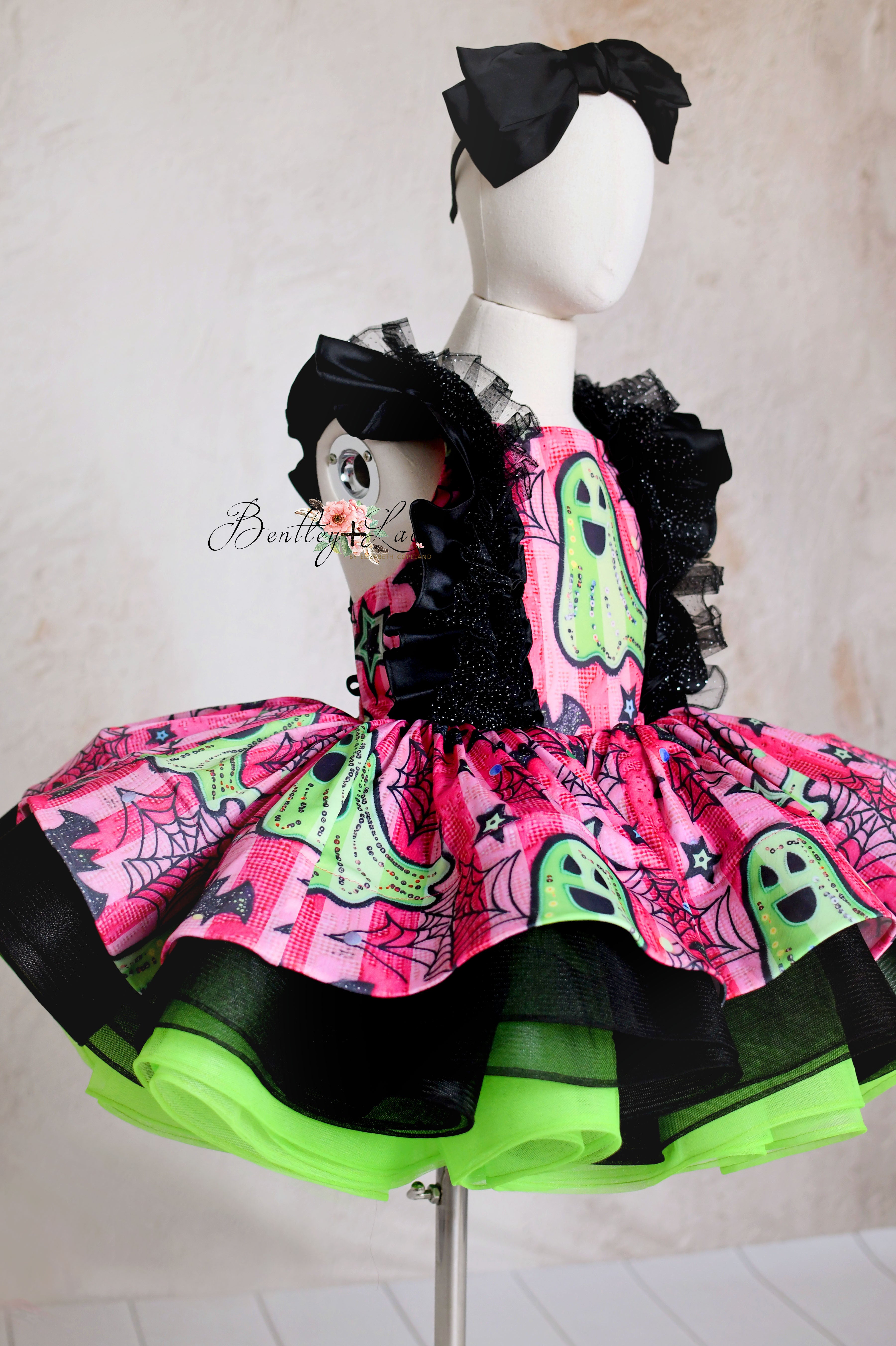 “Detail shot of the bold pink and green ghost-themed fabric on a custom Halloween dress”