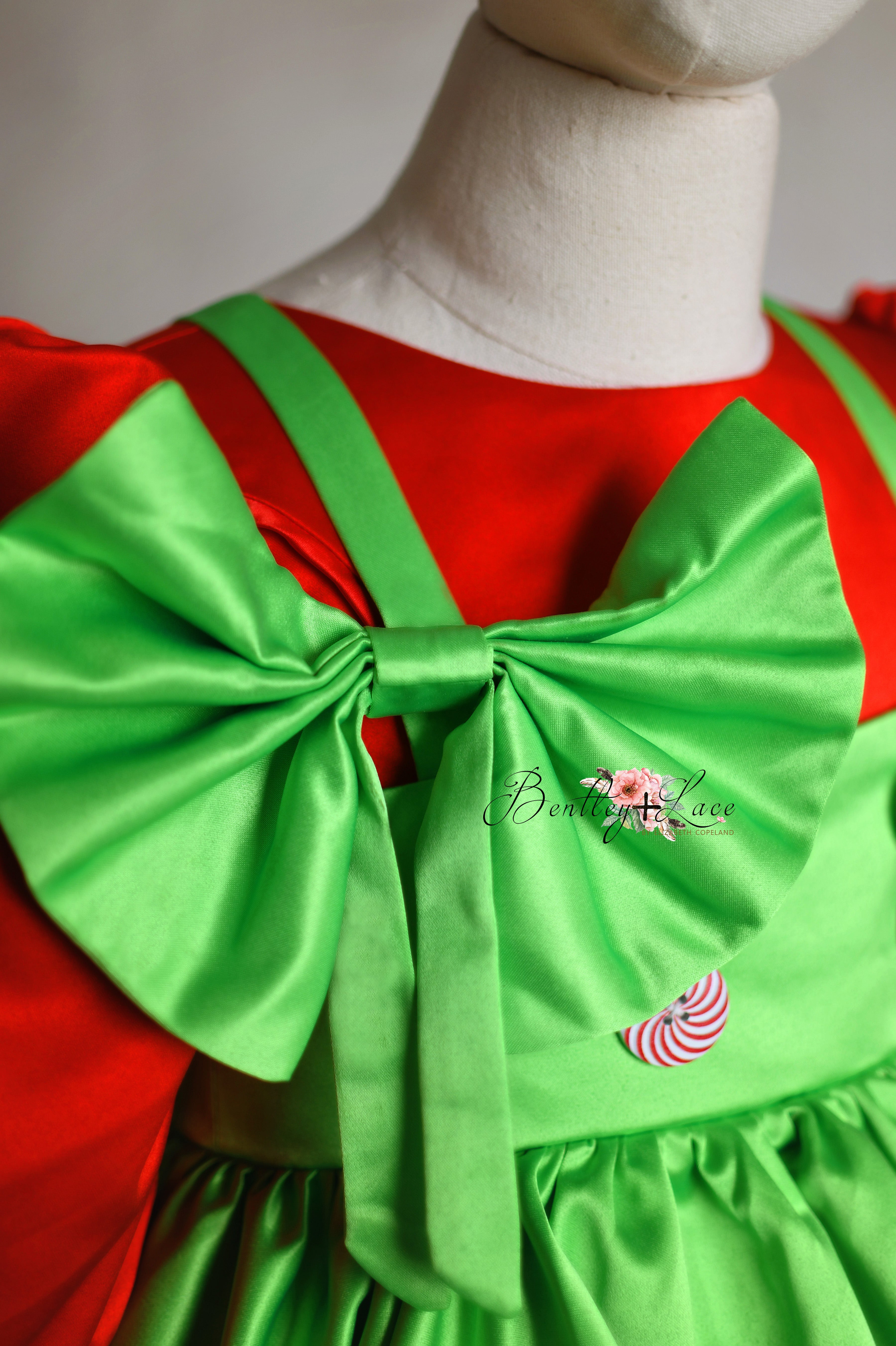 Mischief-Maker Set holiday dress with a detachable green apron, matching bow, and heart embellishments, perfect for photoshoots.