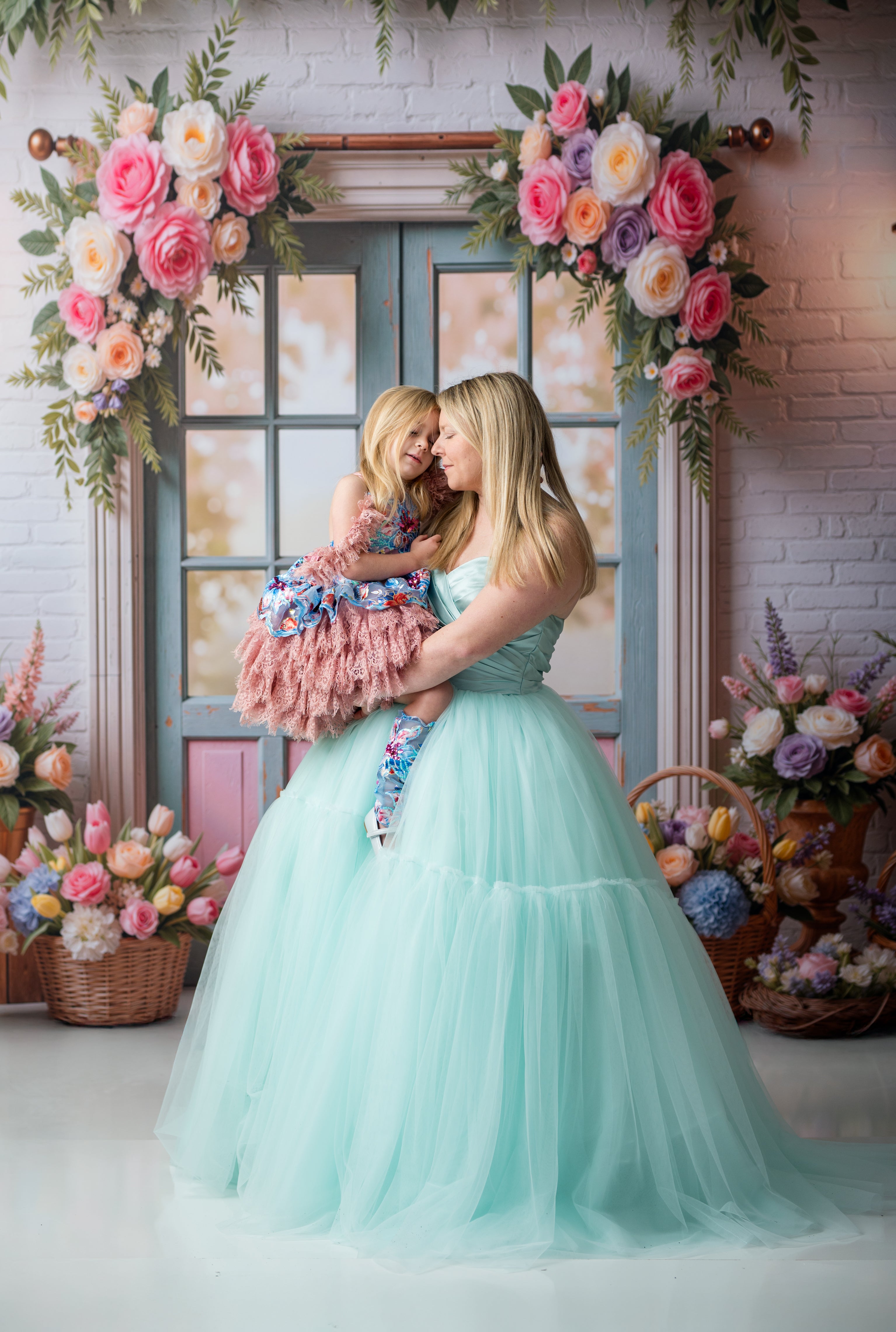 Woman in a light blue dress holding a child in a floral decorated room.