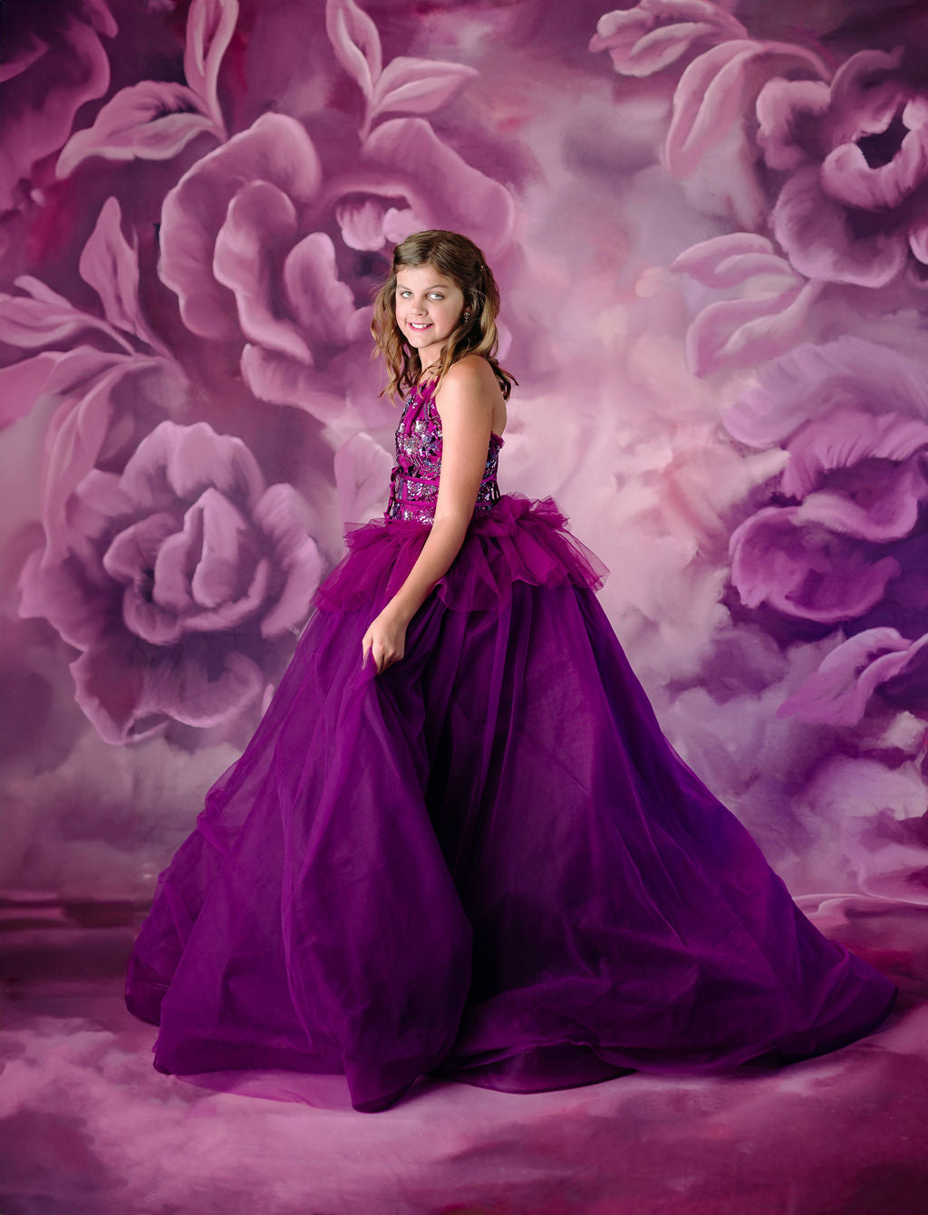 Side profile of a girl in a purple couture dress against a floral backdrop.
