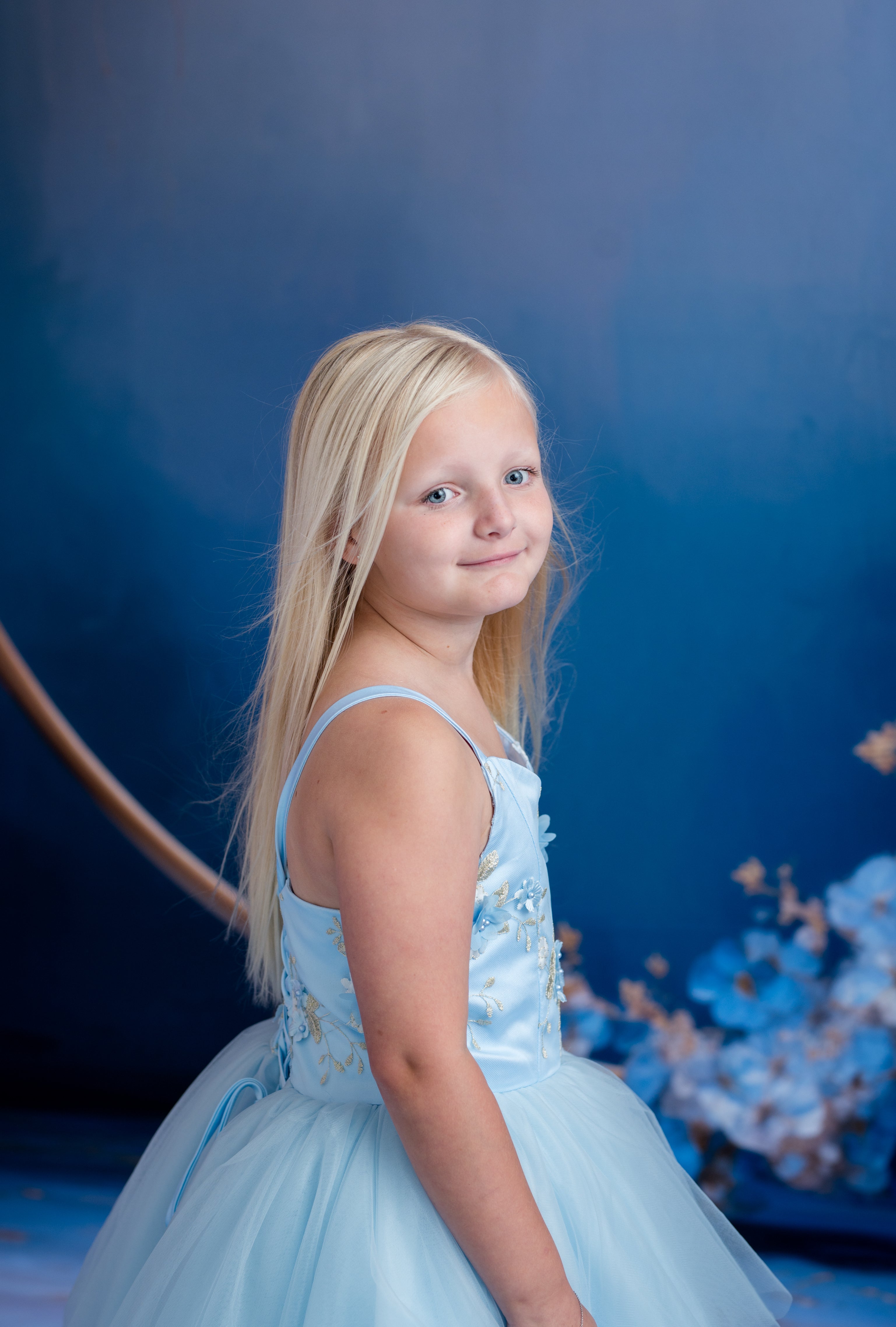 Young girl in a light blue dress against a dark blue background