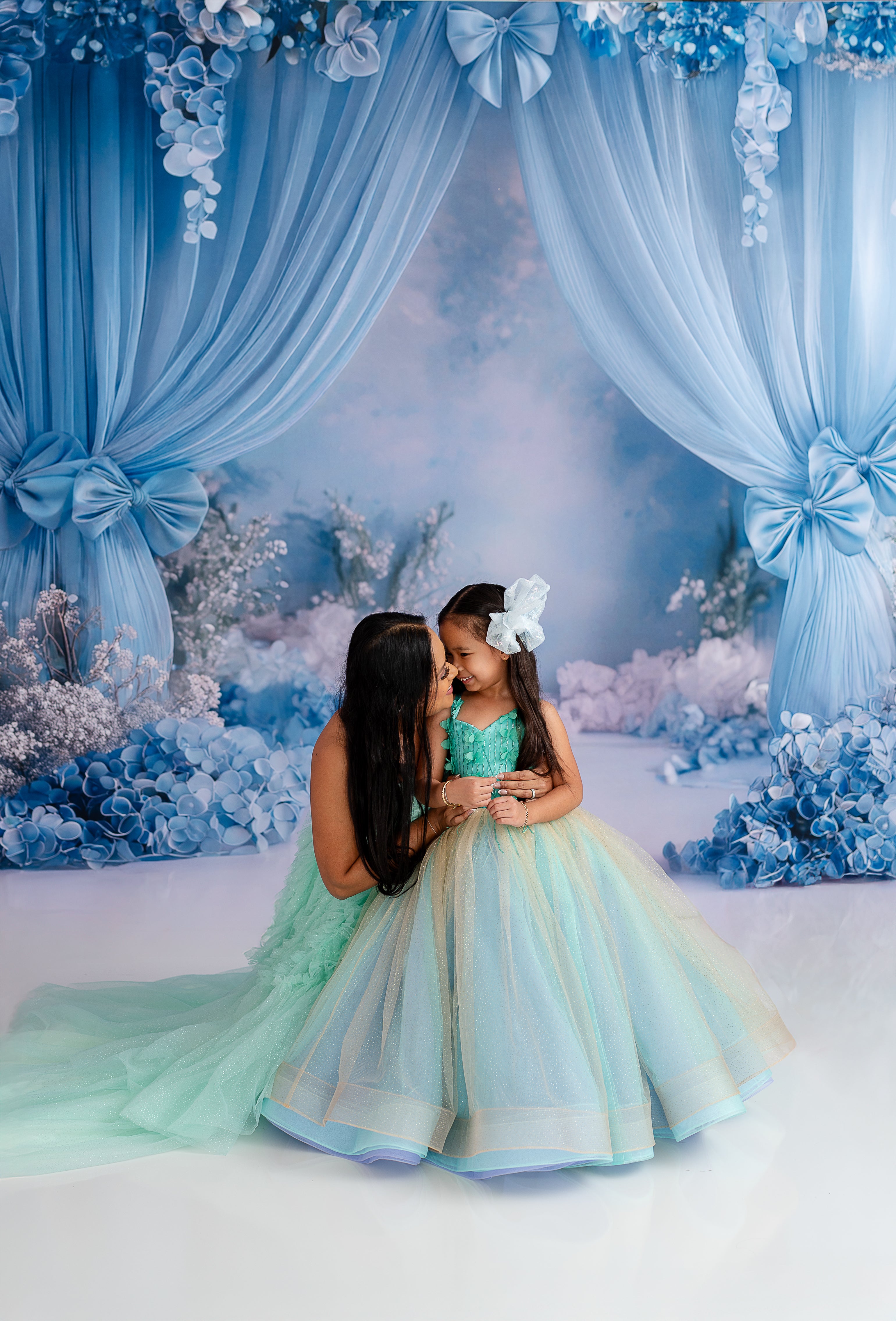 "Graceful mother and daughter pairing in layered gowns, styled for a dreamy photoshoot."