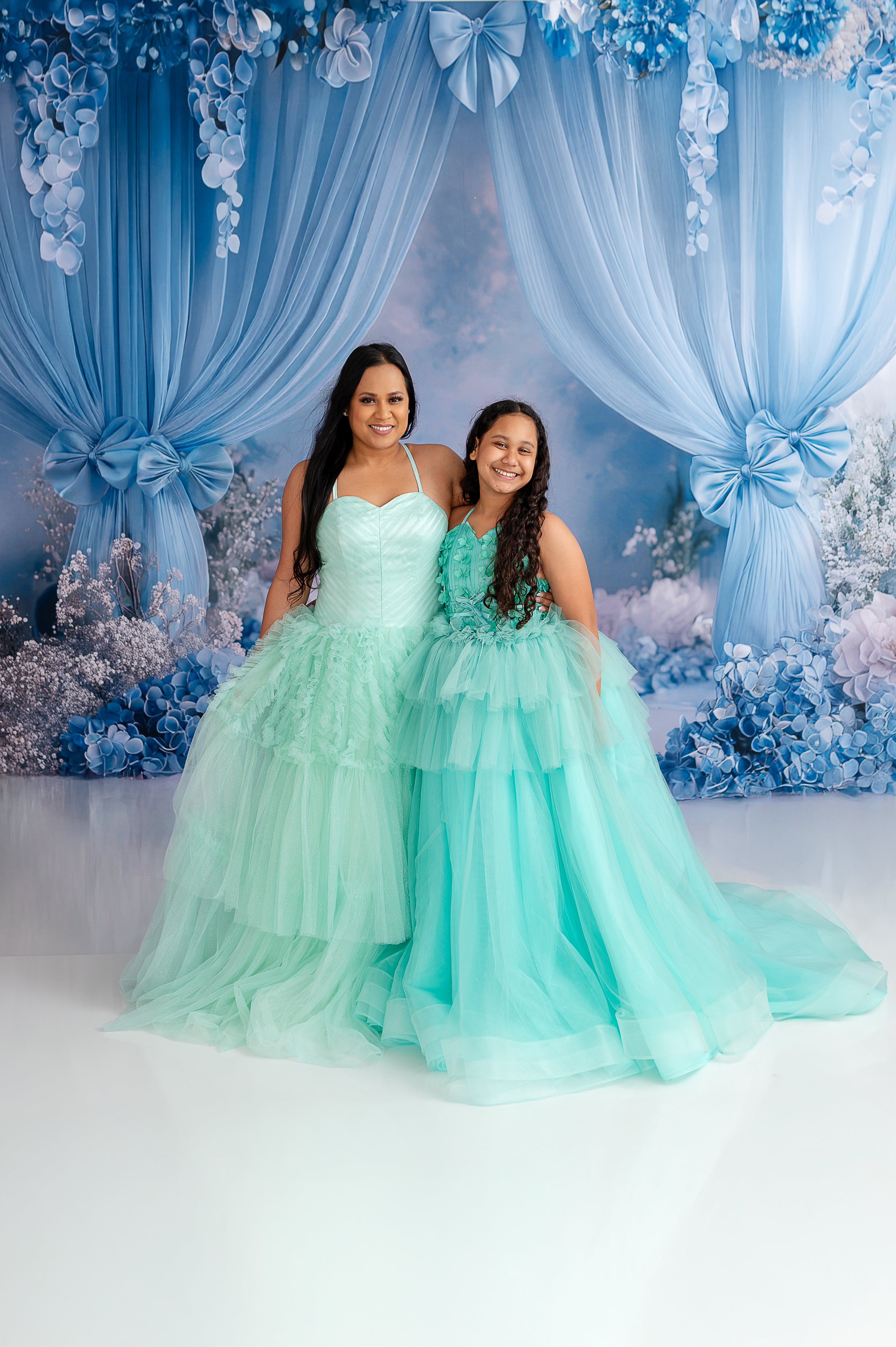 "Mom and daughter glowing in ethereal gowns with soft blue hues, perfect for a styled session."