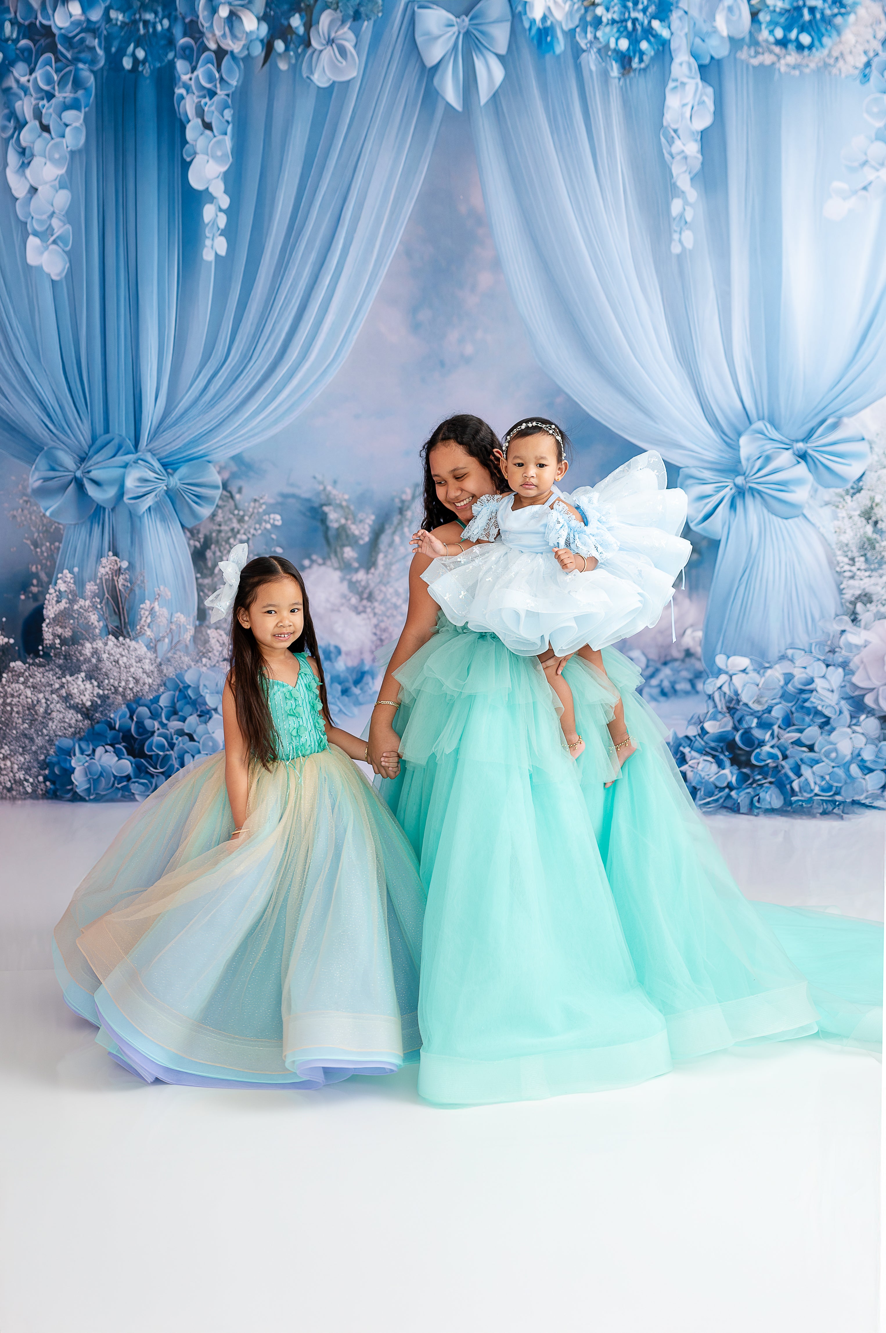 "Mom and daughter share a joyful moment in their flowing layered gowns of aqua and mint."