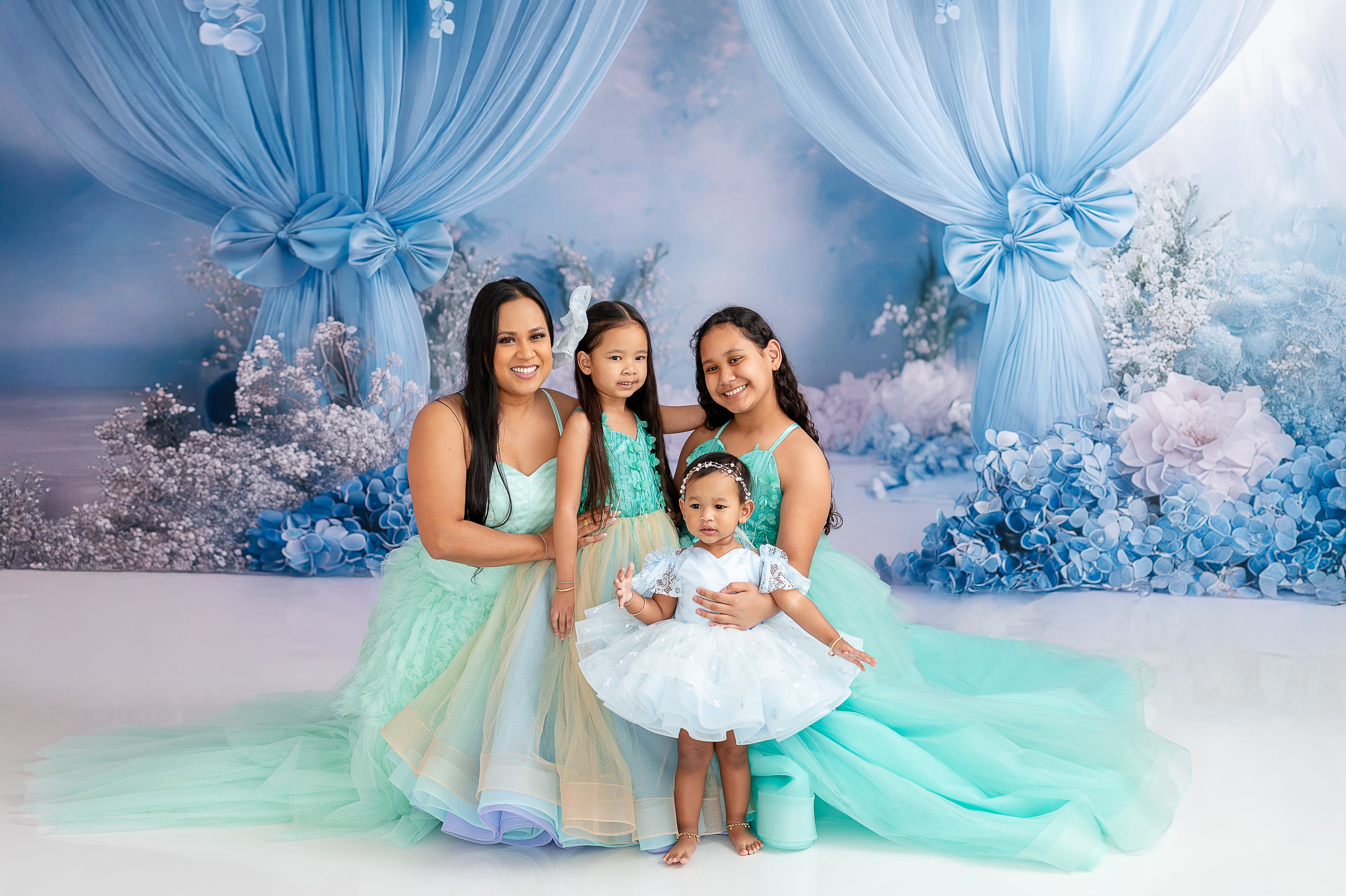 "Mom and daughter share a joyful moment in their flowing layered gowns of aqua and mint."