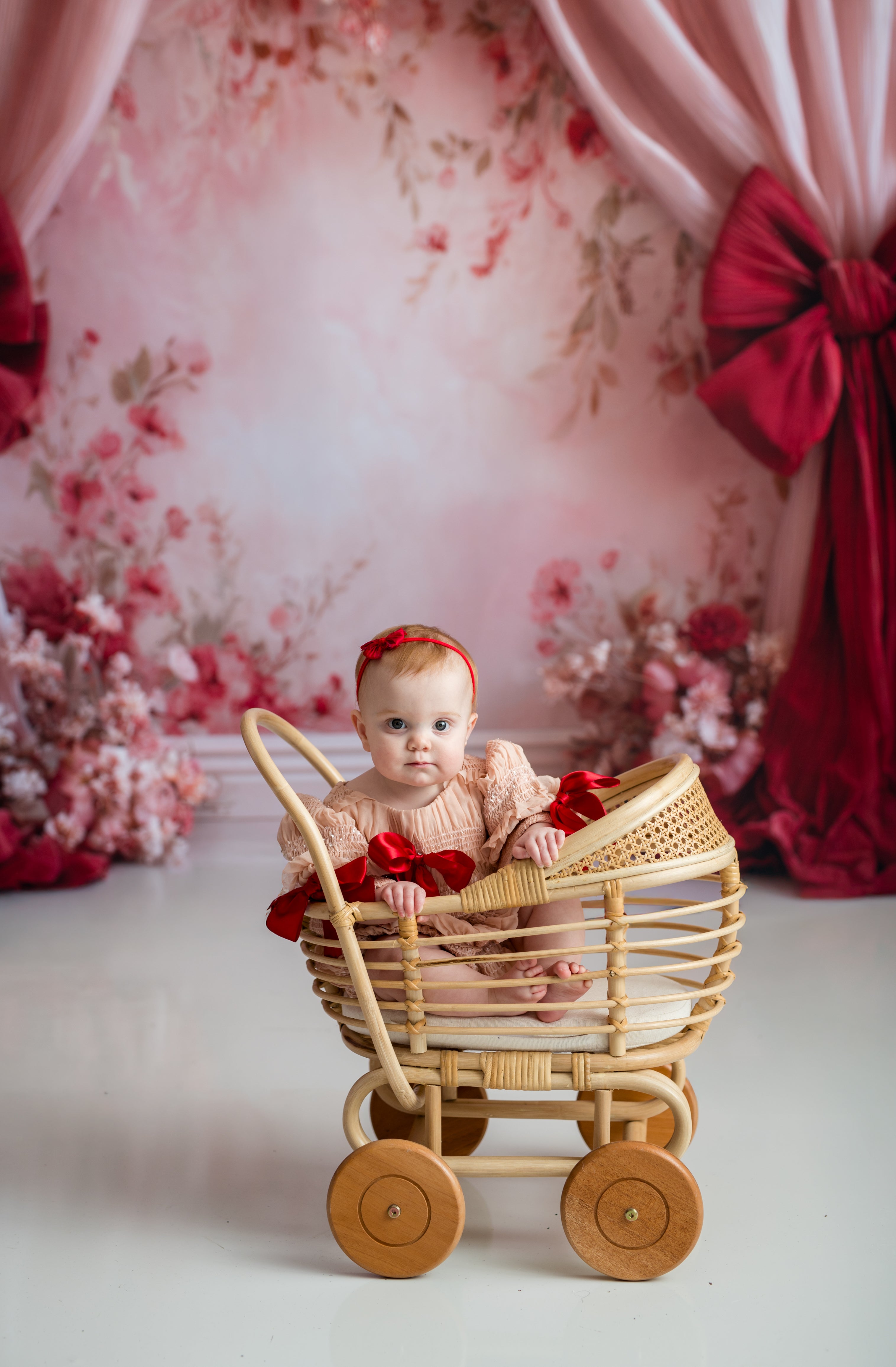 Baby in a decorative setting with a floral backdrop and red accents.