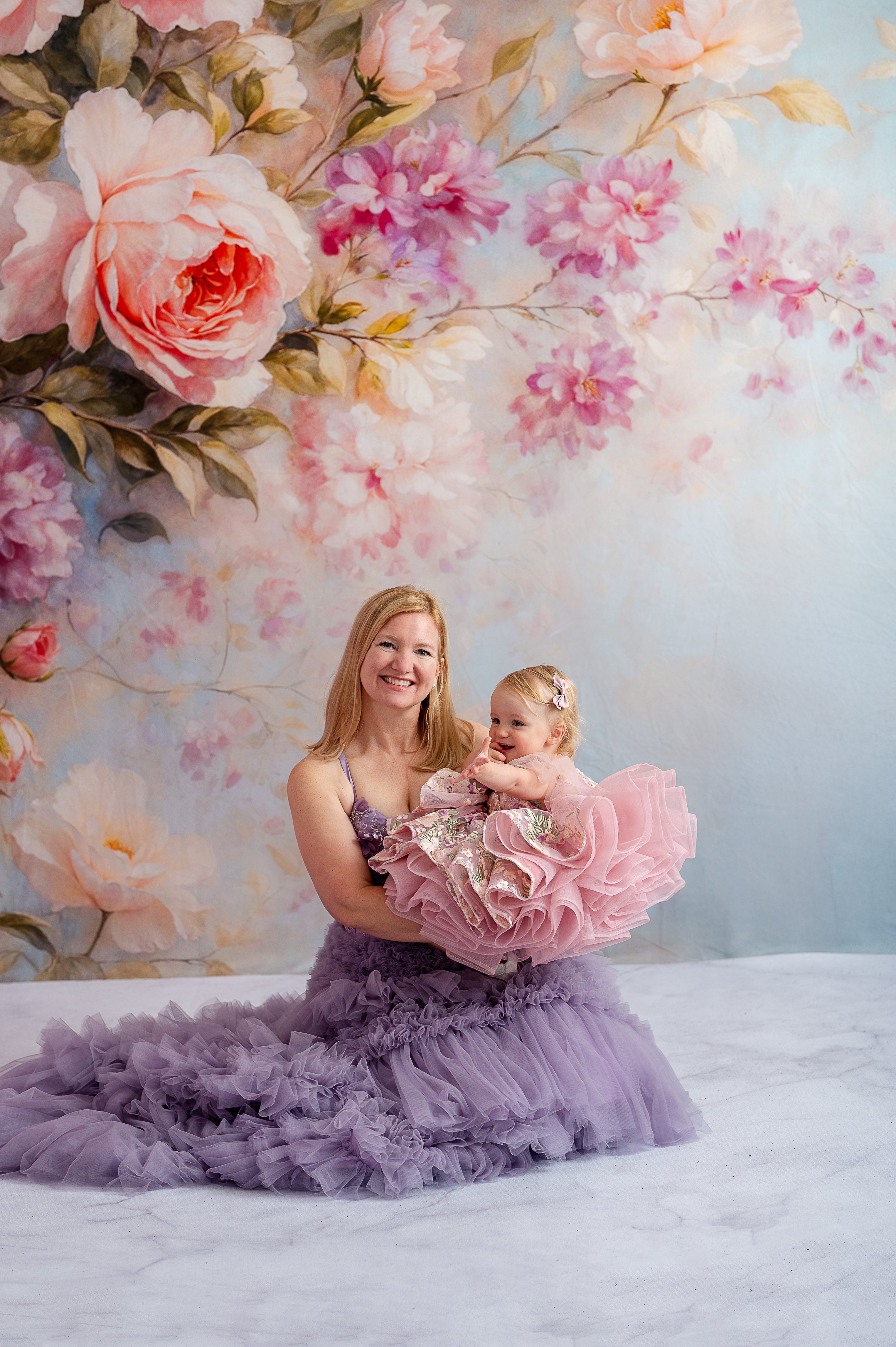 Candid moment between mother and daughter in matching Violet Grace gowns, laughing together in nature.
