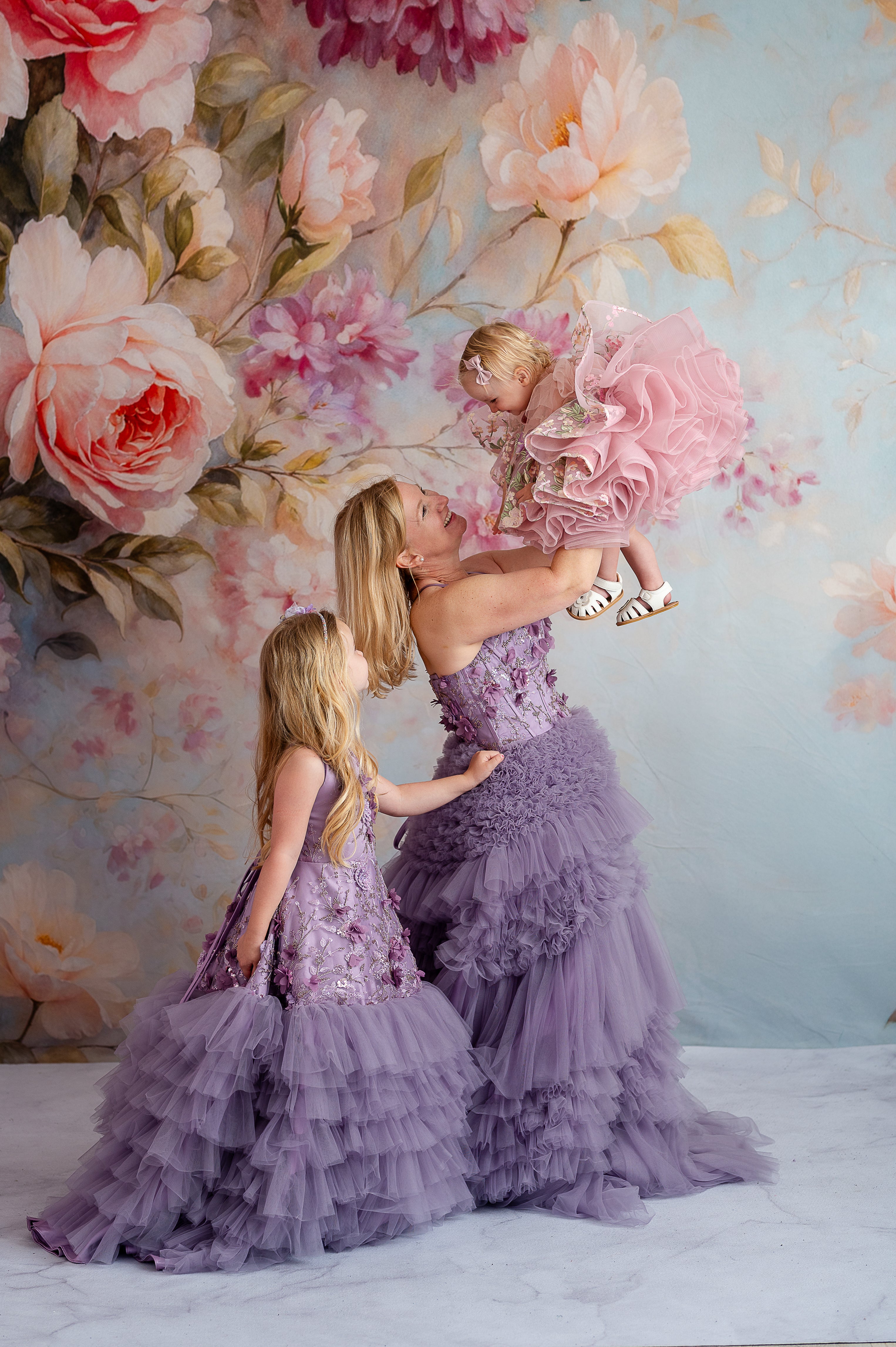 Mom and daughter in matching lavender gowns with floral appliqués during golden hour photoshoot.