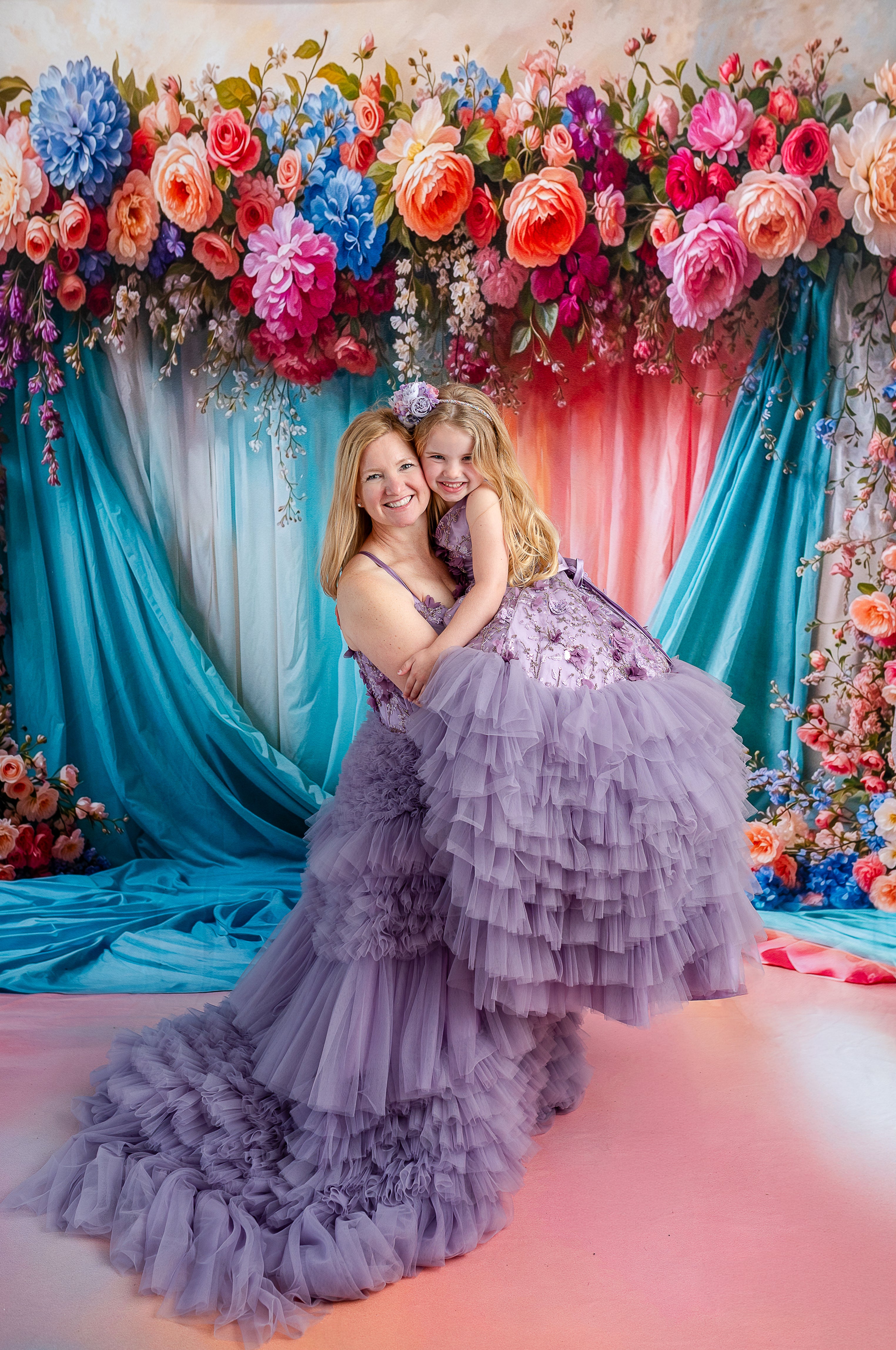 Mommy and me portrait in coordinating Violet Grace lavender tulle gowns surrounded by flowers.