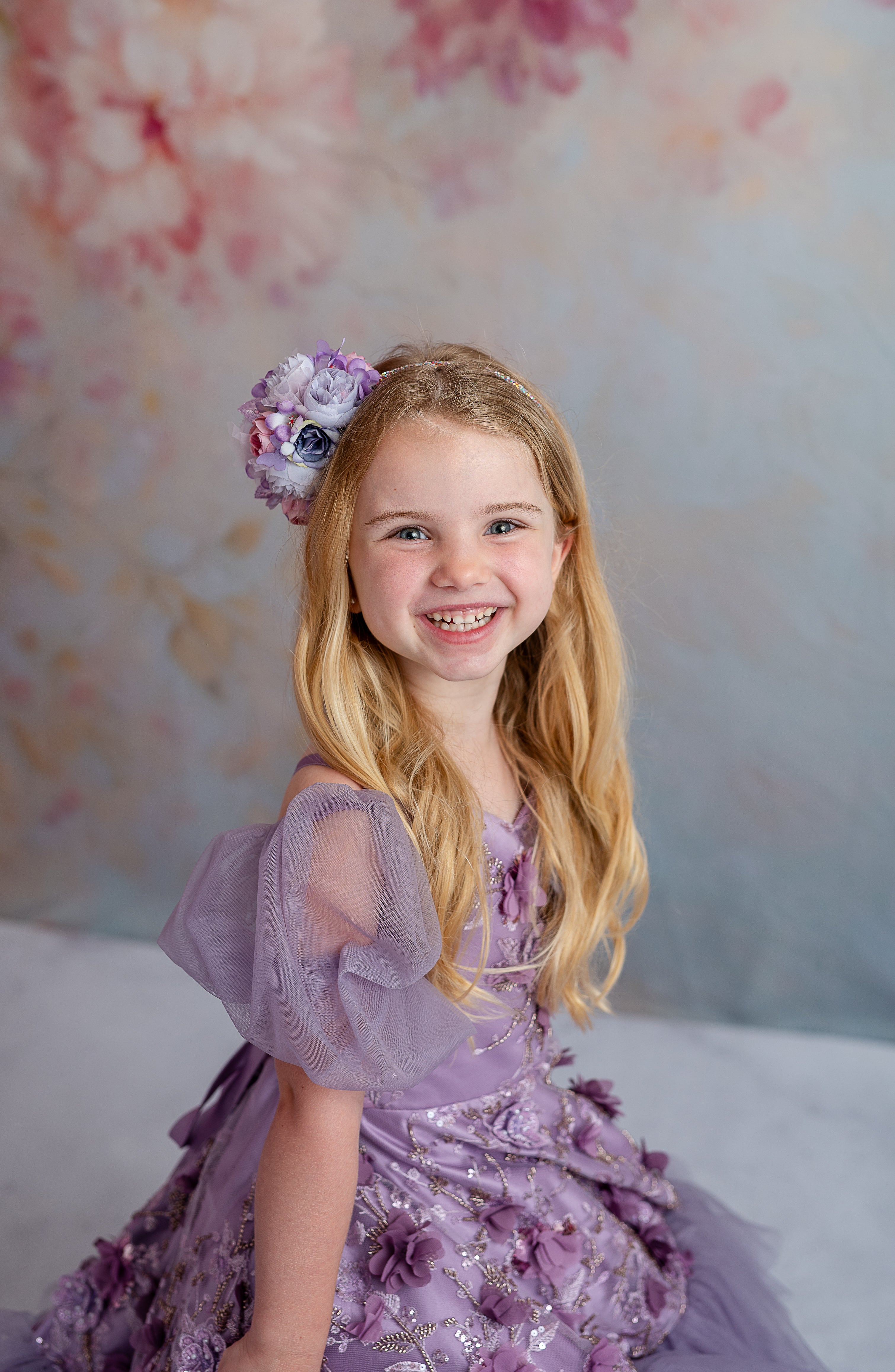Side profile of young girl in lavender floral gown with full tulle skirt and soft sleeves.