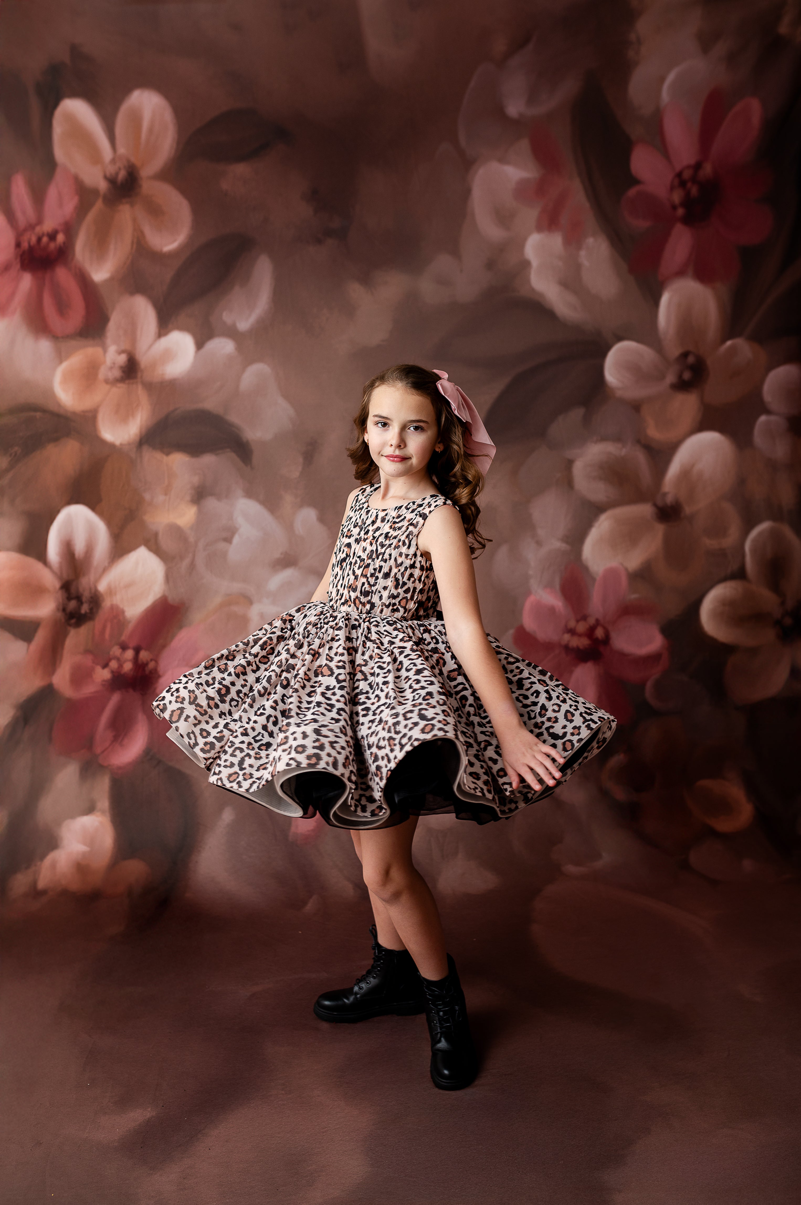 "Modern and timeless: a little girl in a leopard dress poses gracefully for a birthday or event-themed photoshoot."