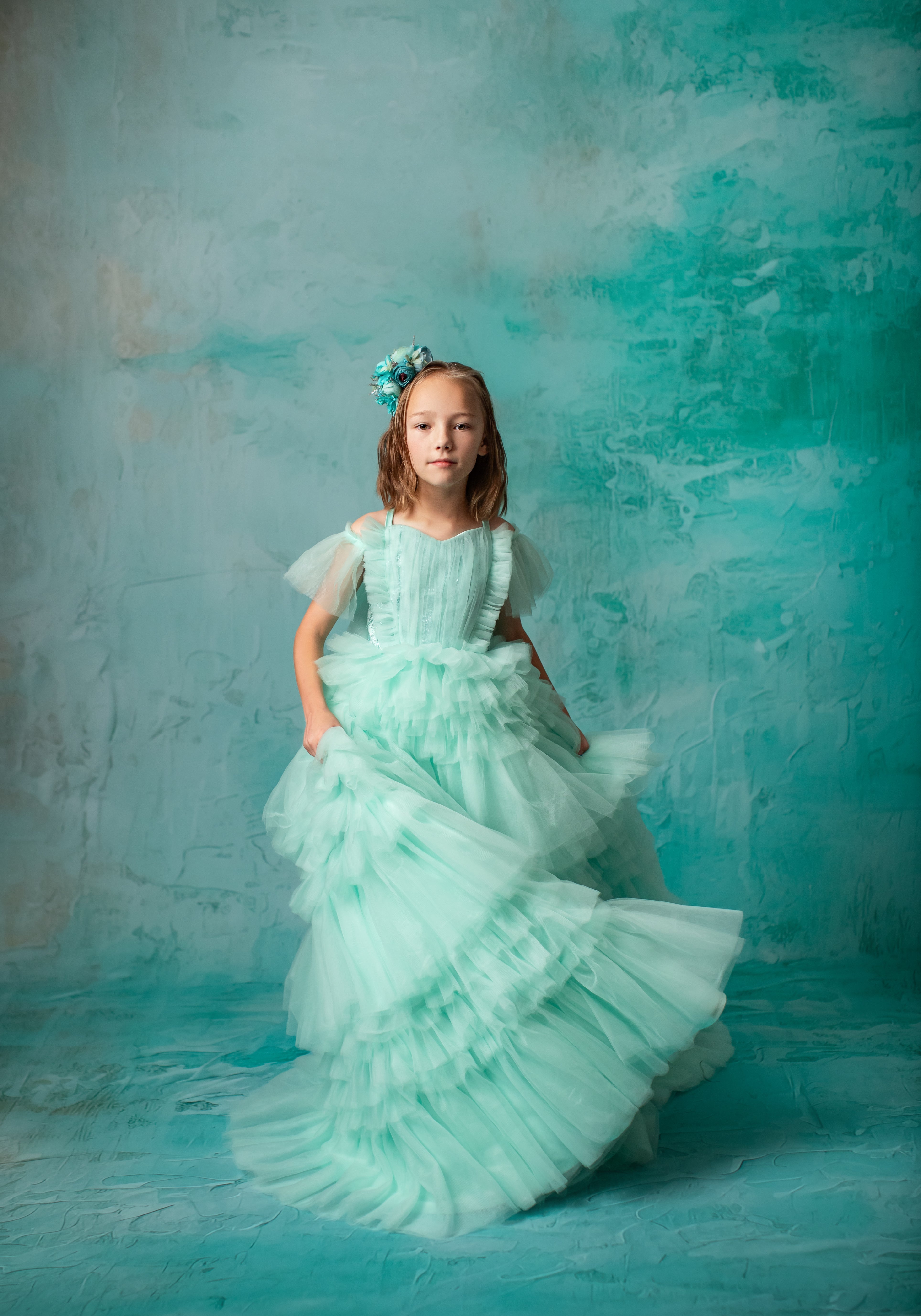 "Child wearing a mint green tulle gown, perfect for special occasions."