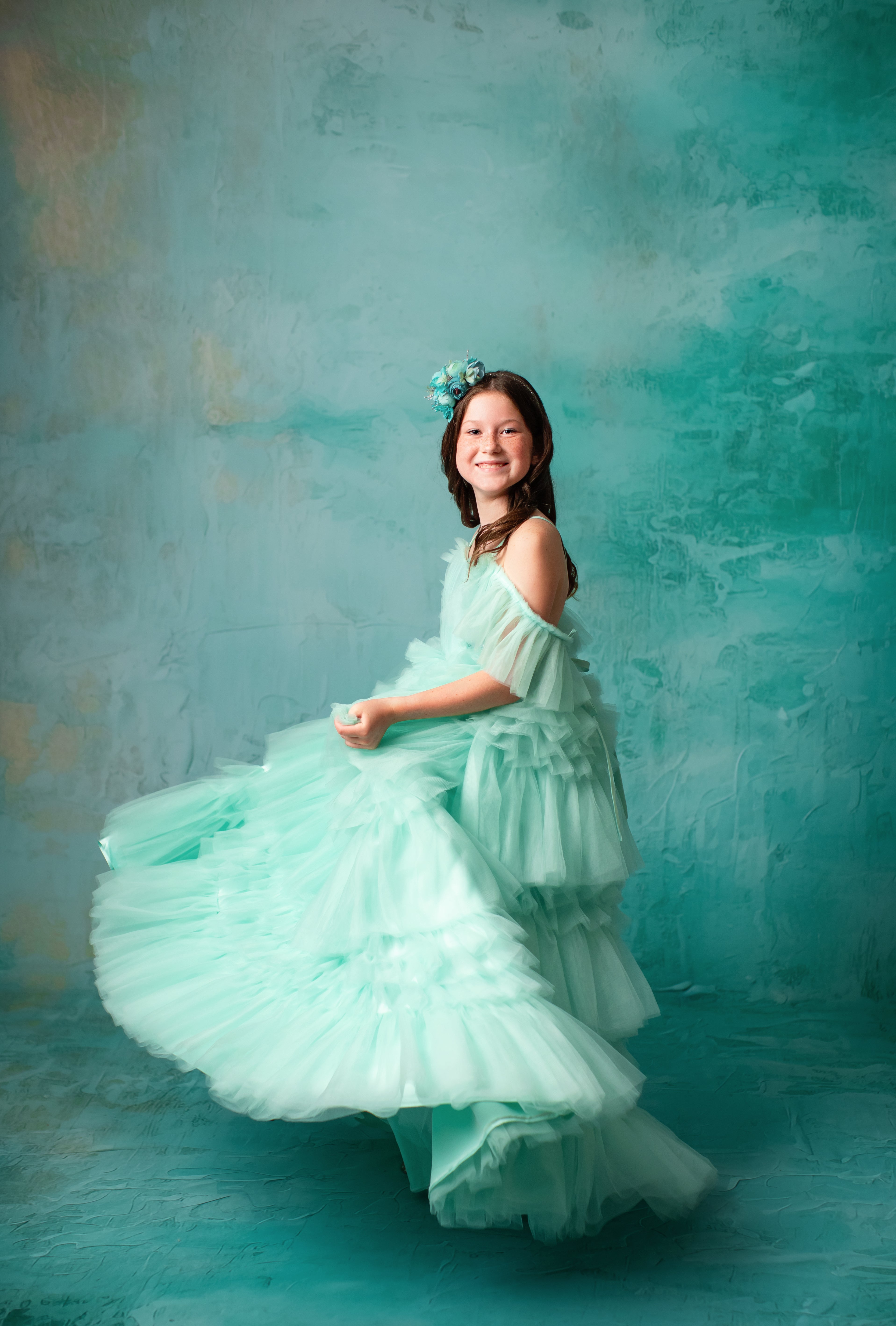 "Child model wearing a dreamy mint green tulle dress with cascading ruffles."