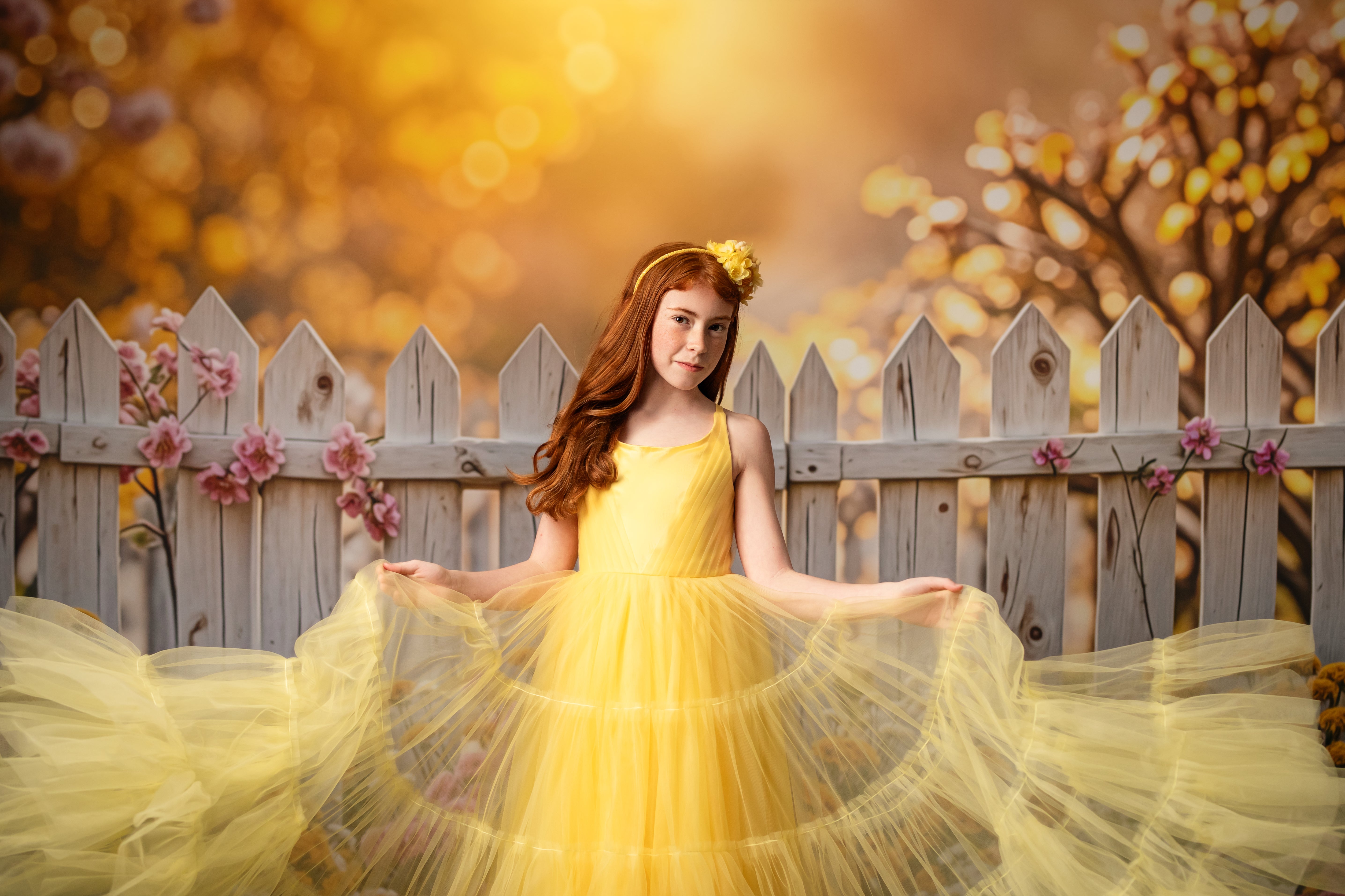 Whimsical wonder – A young model in a yellow gown twirls gently, her soft curls and delicate pose capturing the essence of childhood magic.