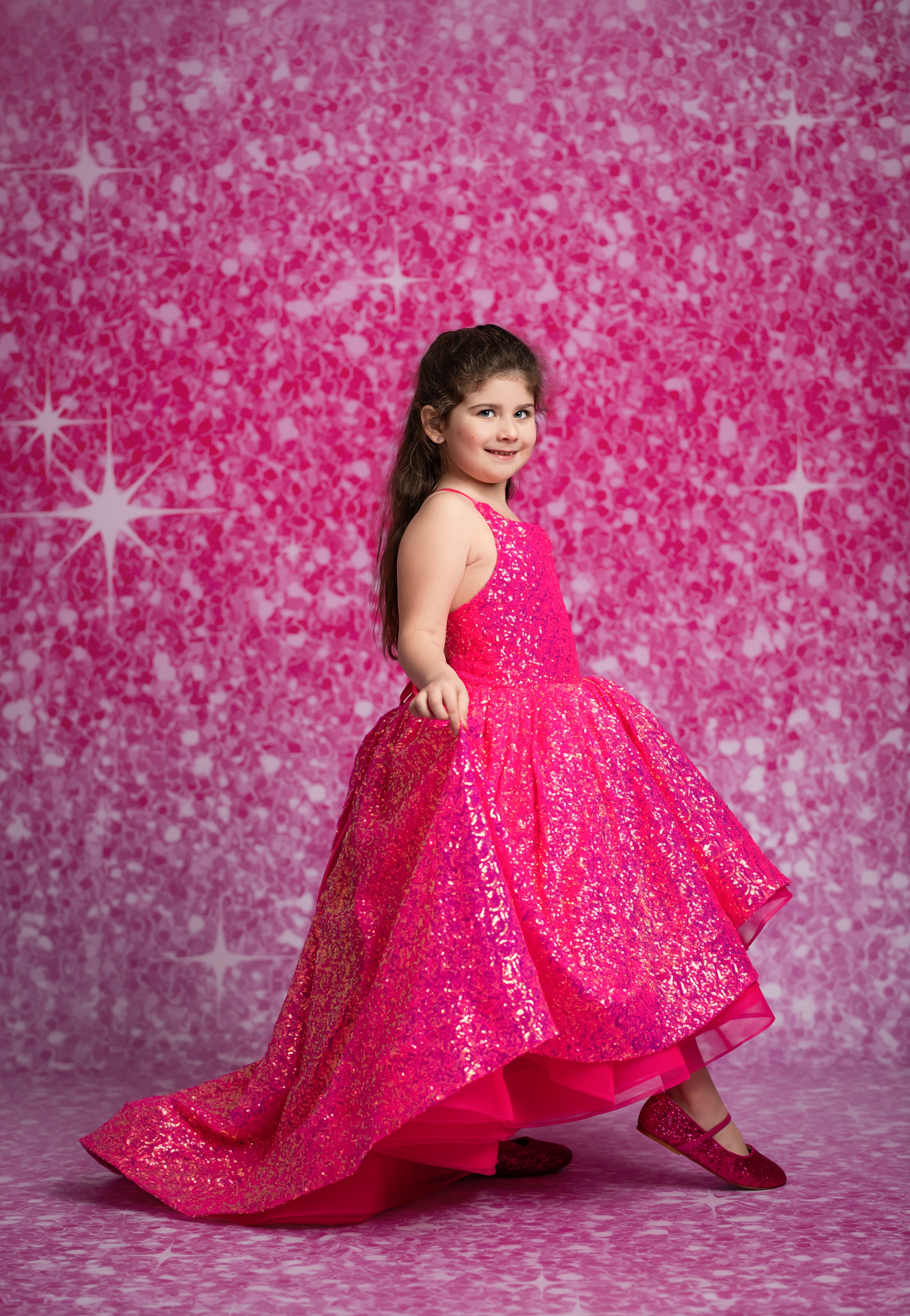Young girl in a bright pink dress against a pink starry background