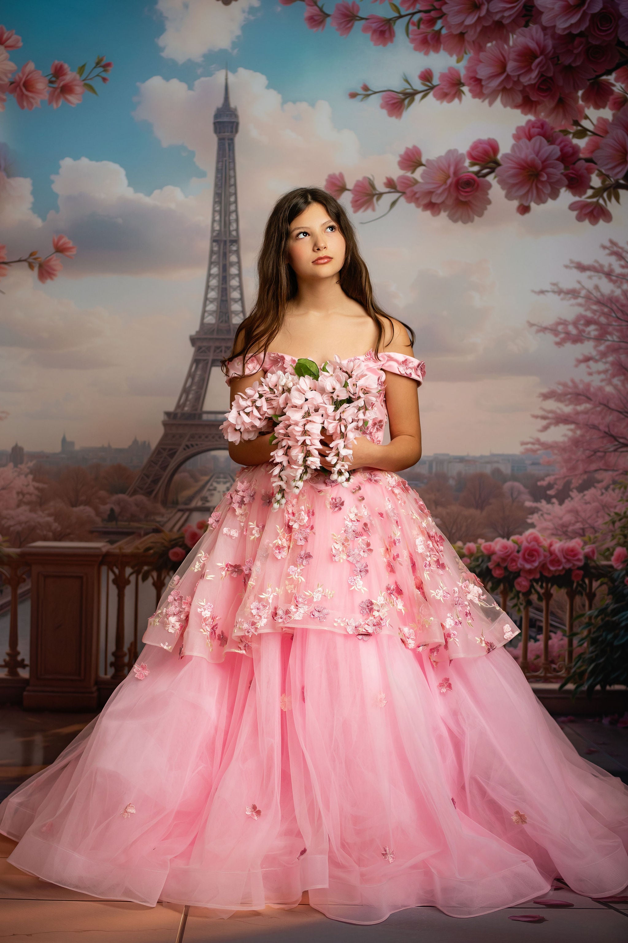 Woman in a pink dress holding flowers with the Eiffel Tower and cherry blossoms in the background