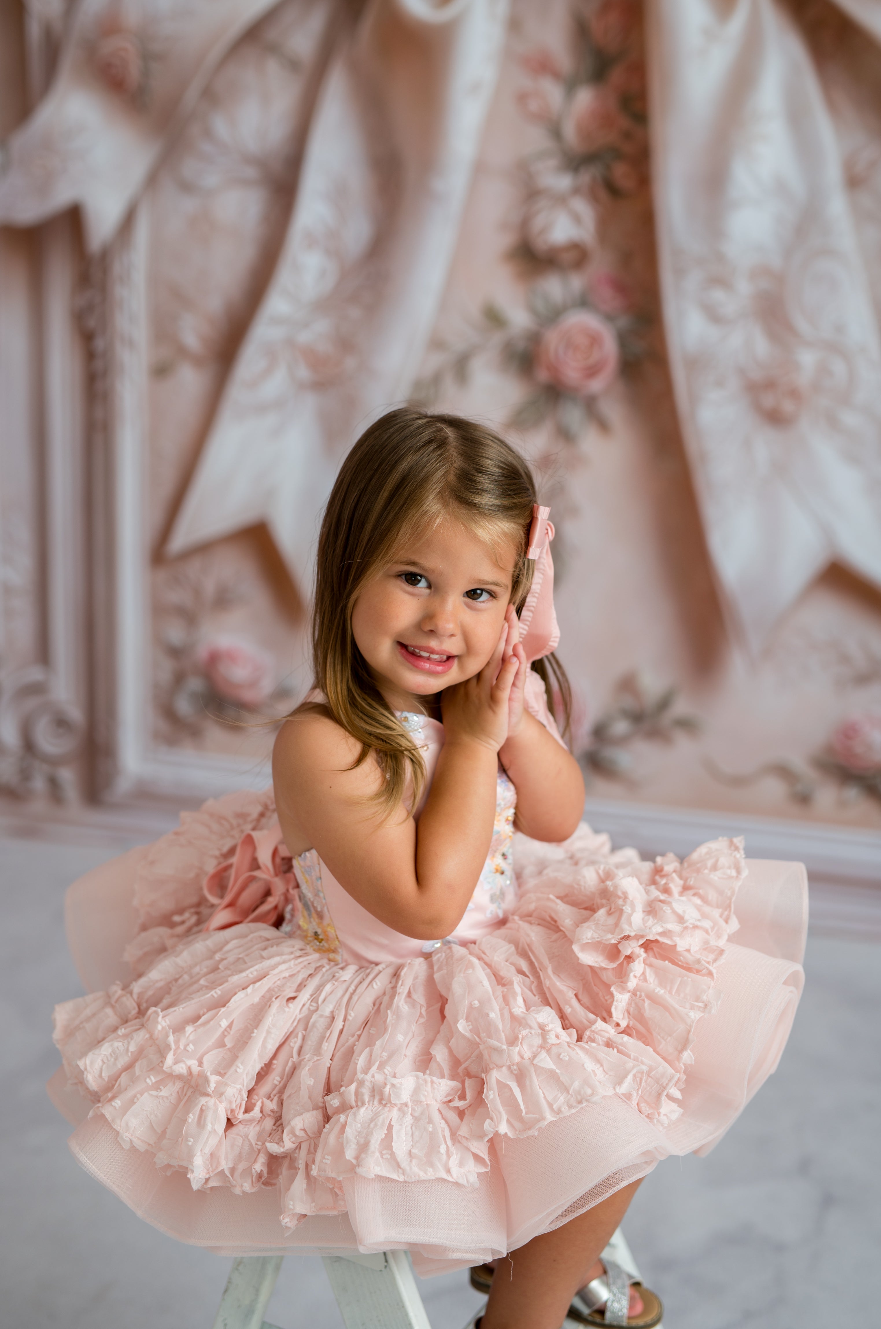 Young girl in a pink dress posing in a decorative room.
