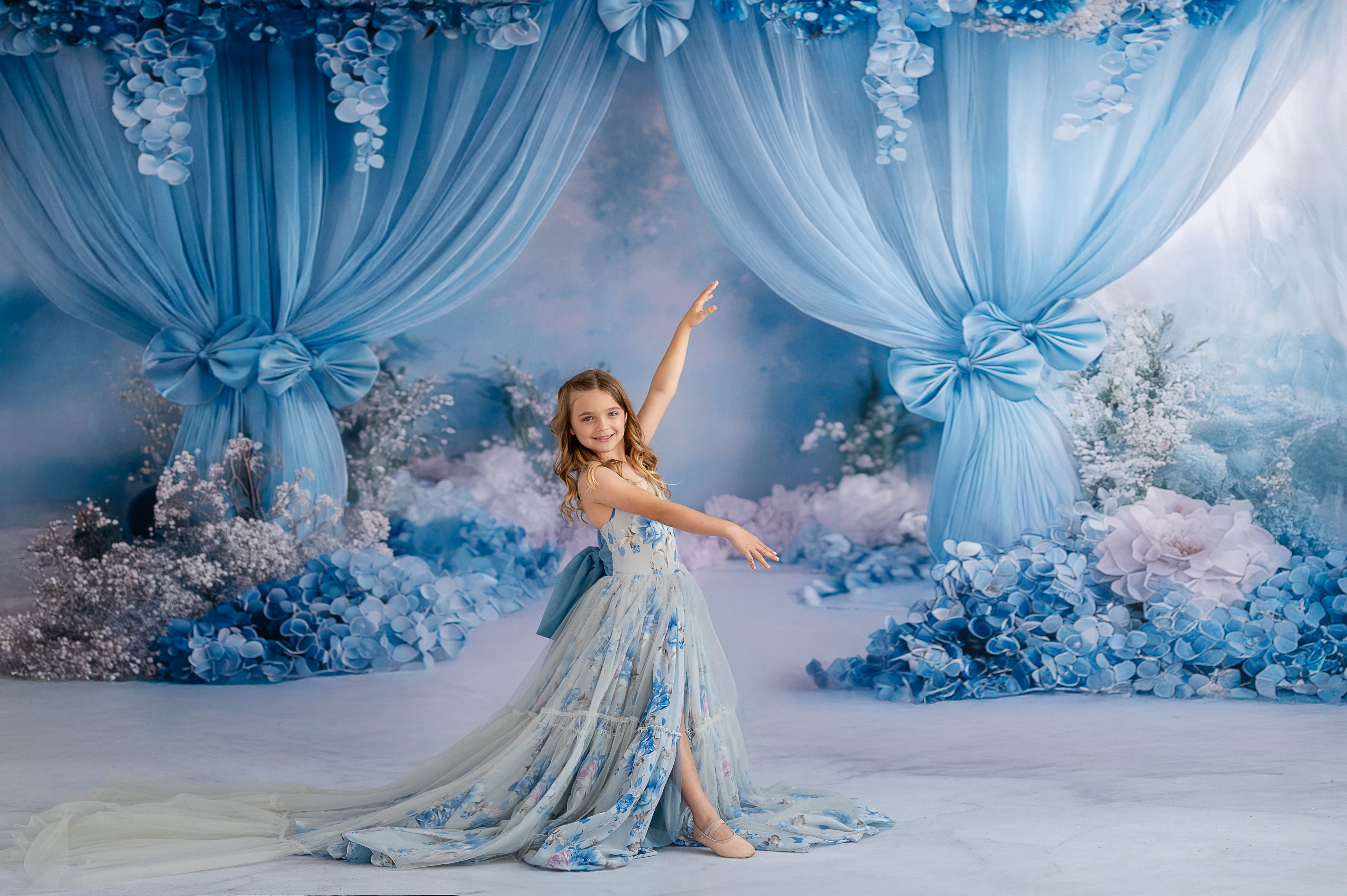 Young model in Hillary gown posing against soft floral backdrop.