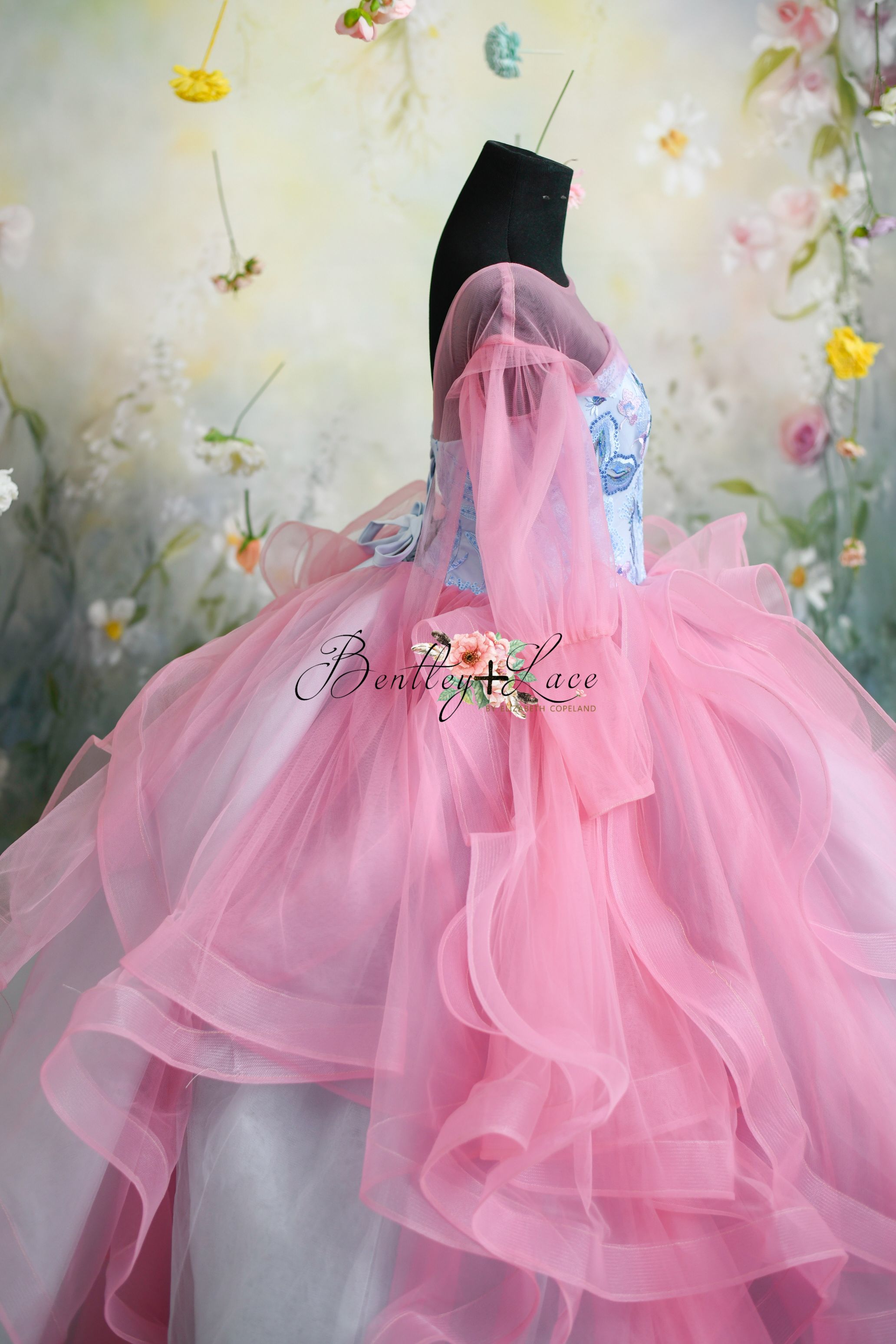 Designer pink and blue gown with floral bodice and layered pink ruffles.