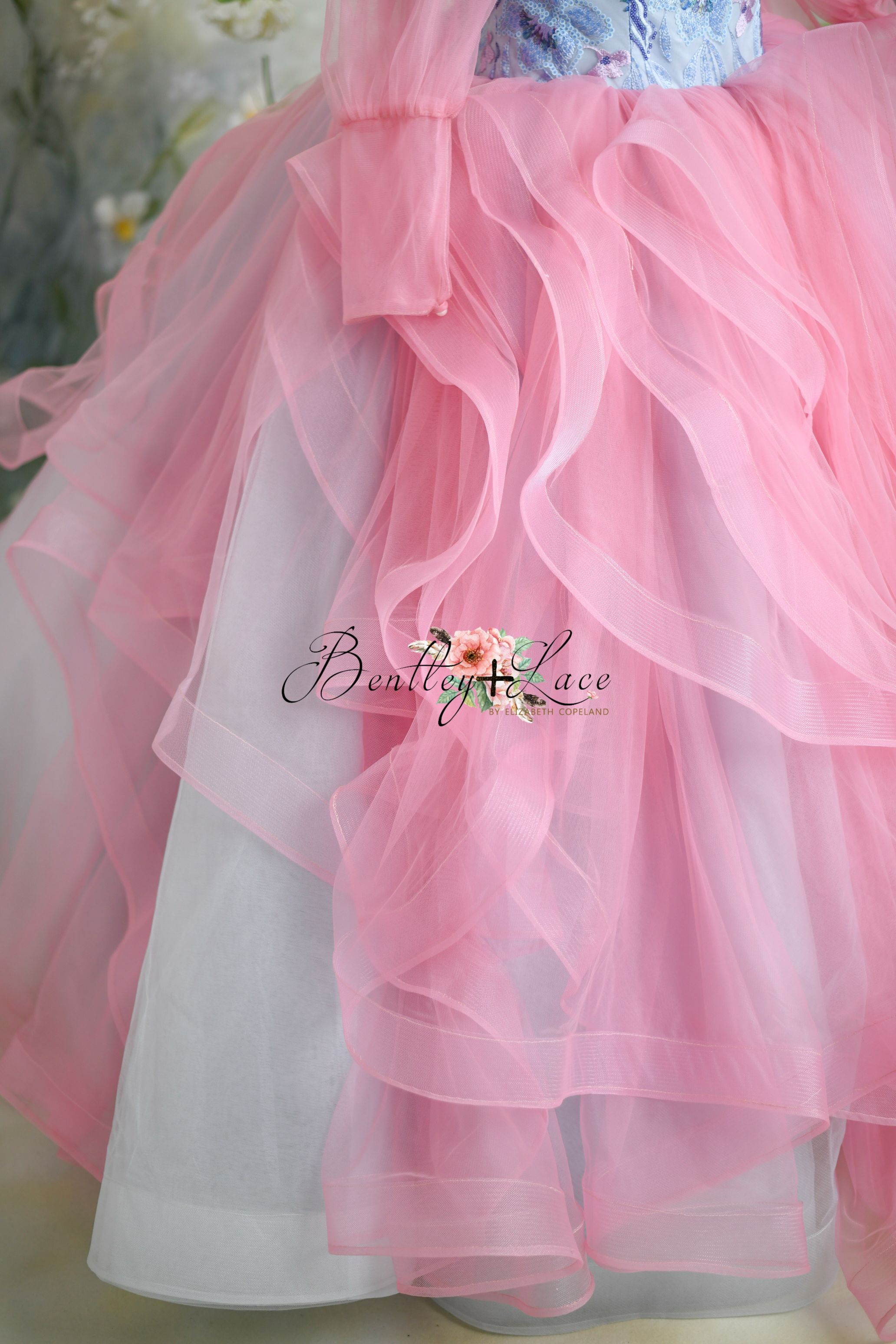 Enchanting pink princess gown with blue floral details and sheer puff sleeves.