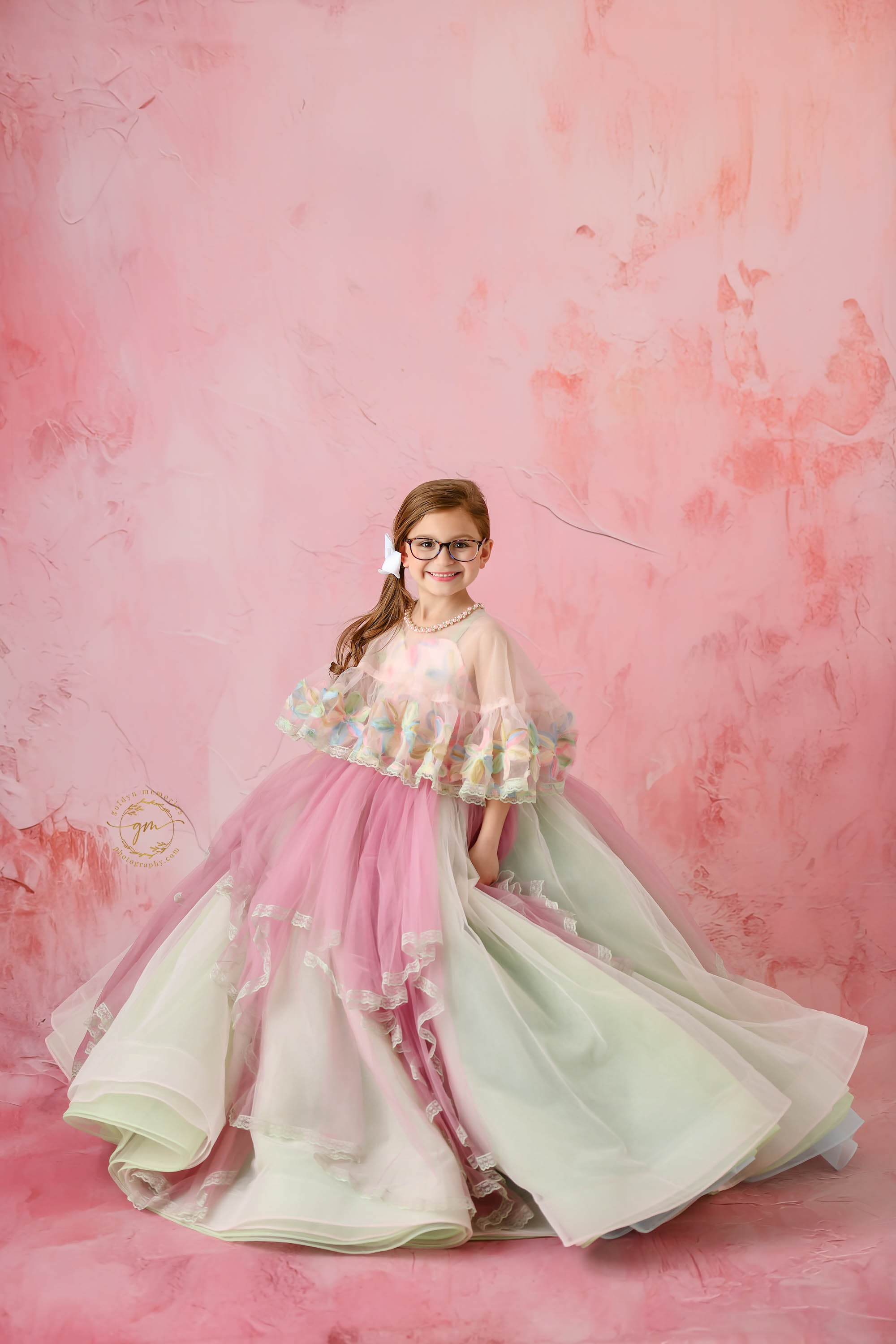 A young girl in a fairytale-inspired floral gown, covered in vibrant blossoms and soft tulle.