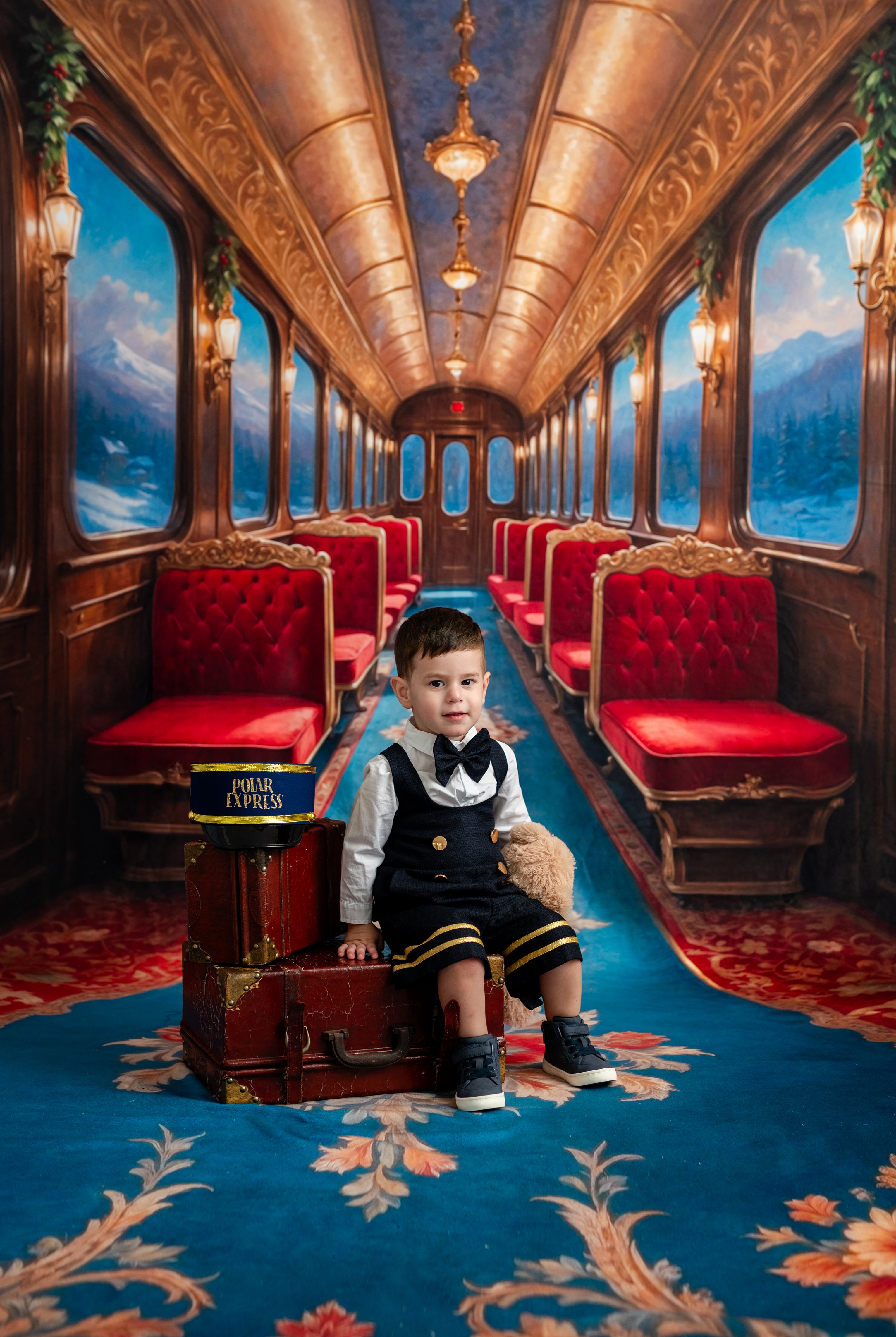 Child in a formal outfit sitting on a suitcase in an opulent train car with red seats and decorative ceiling.