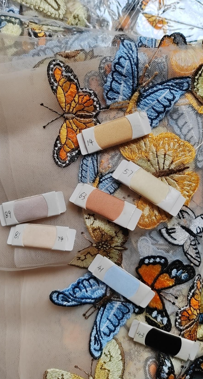Butterfly-themed makeup swatches on a textured surface