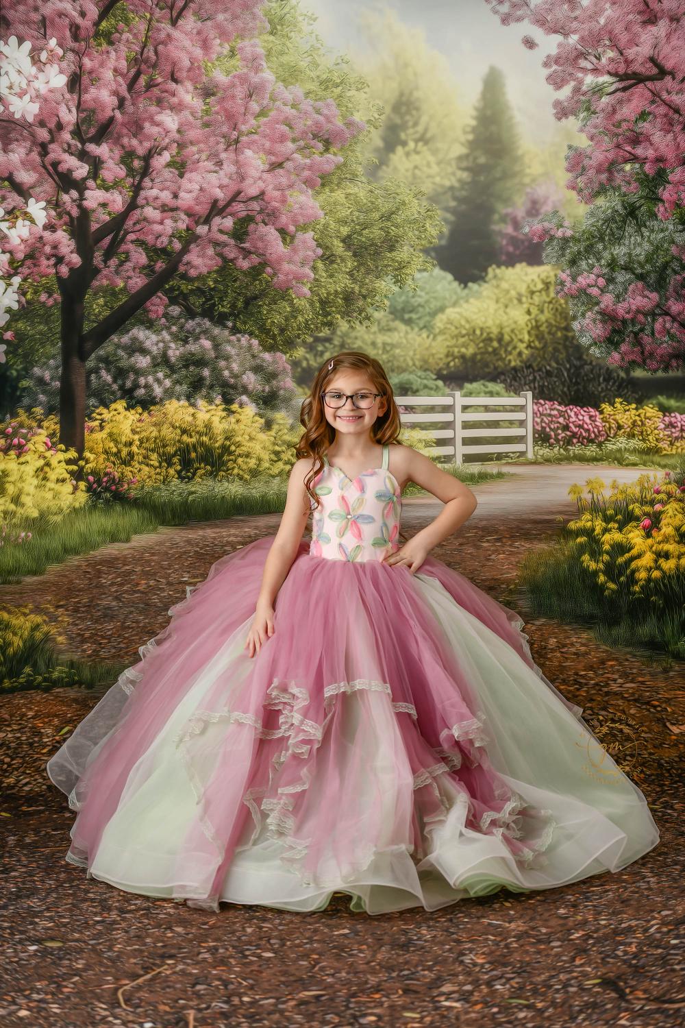 "Beautiful floral dress worn by a smiling girl in a garden setting."