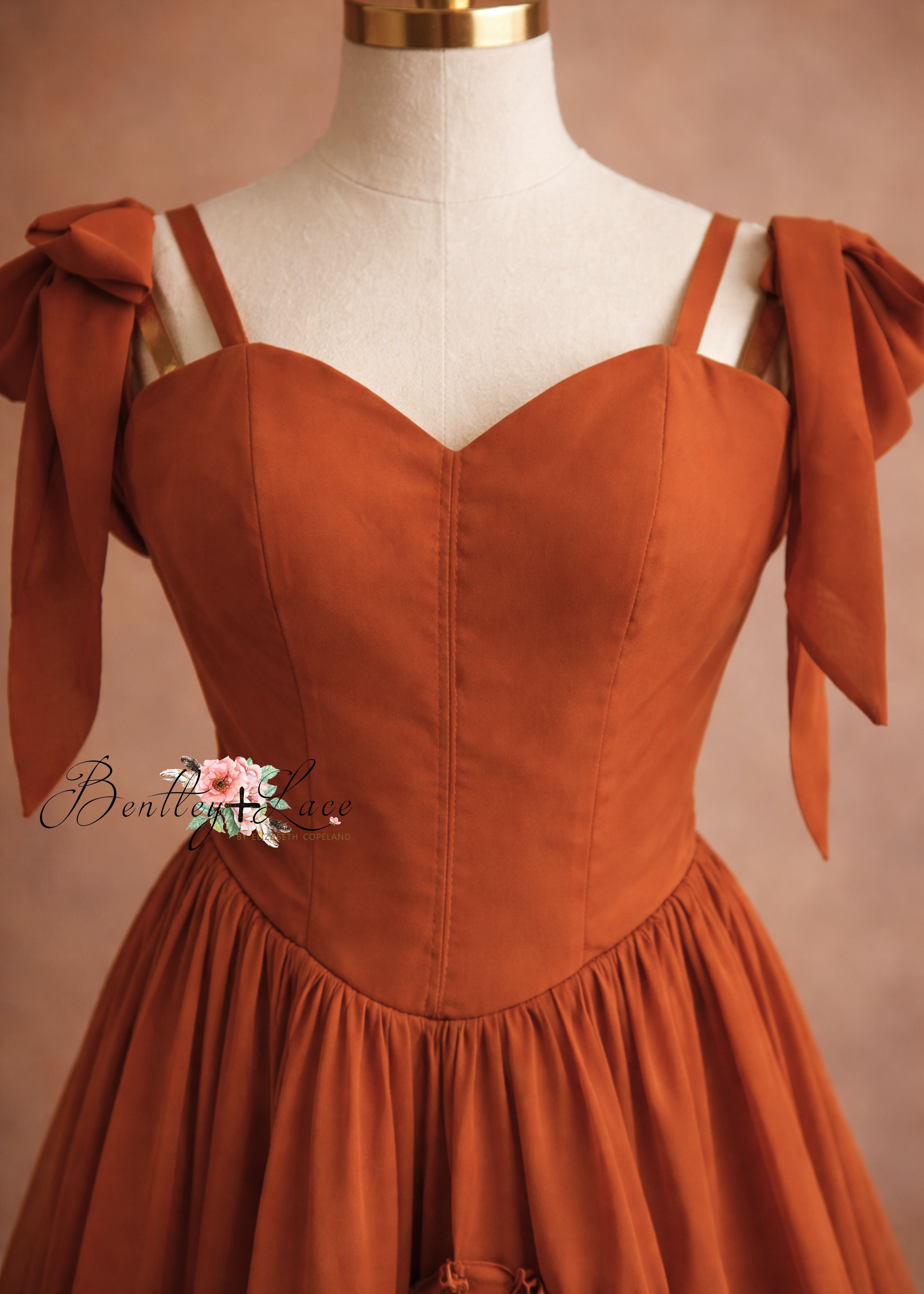 Brown dress with bow straps on a mannequin against a beige background