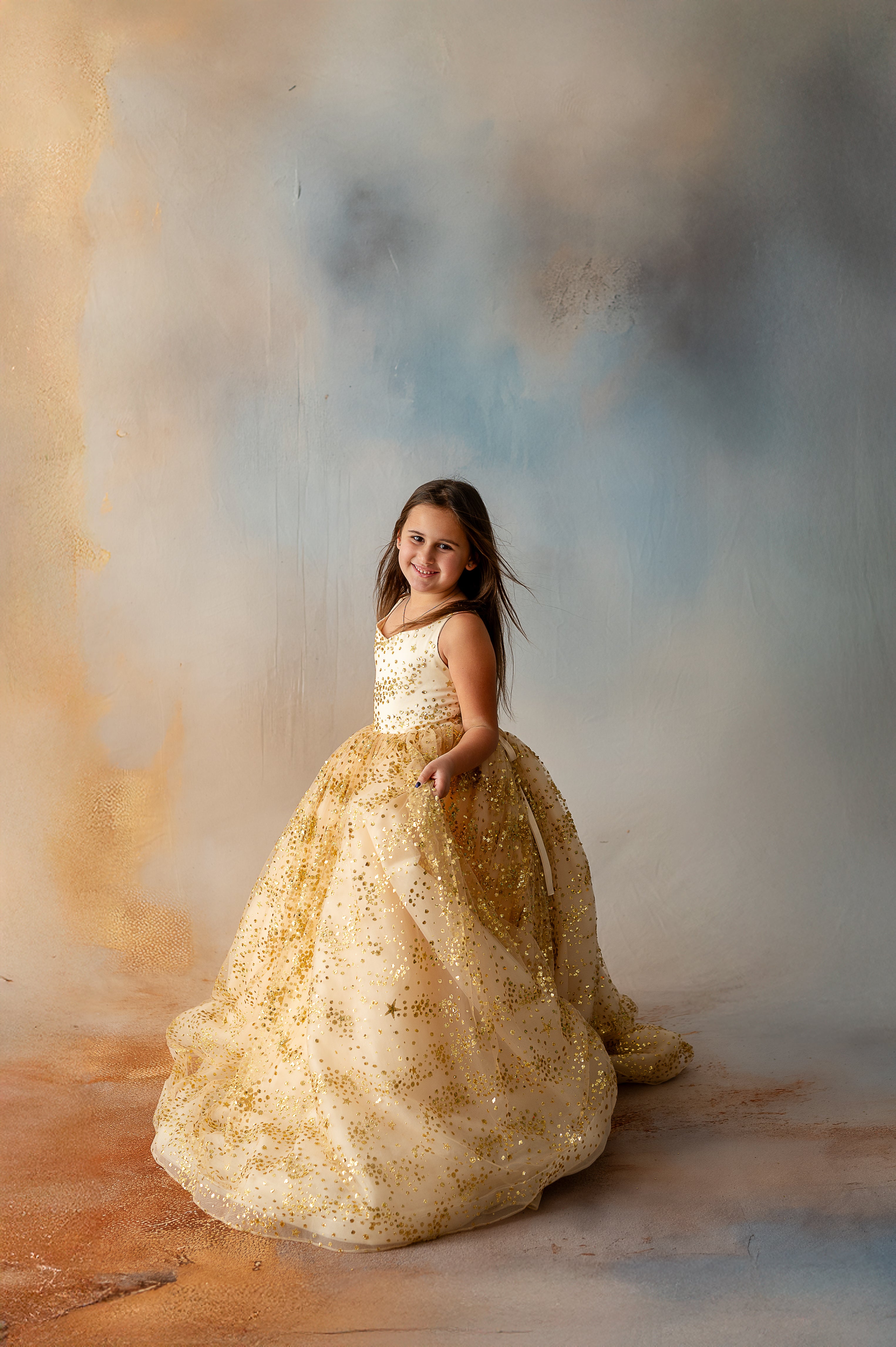 Girl holding gown skirt, showcasing gold star details