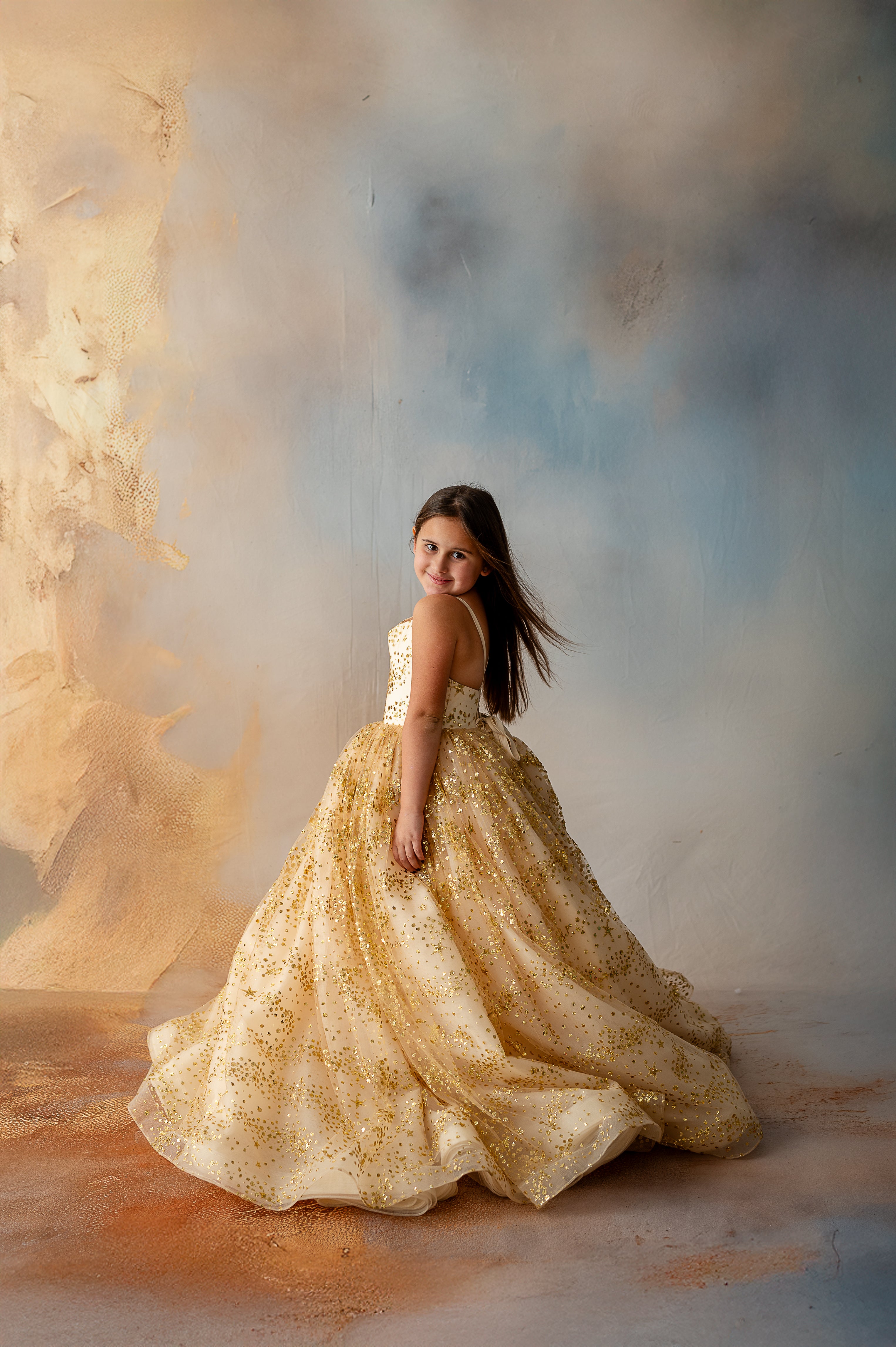 Gold stars catching the light on girl’s twirling gown