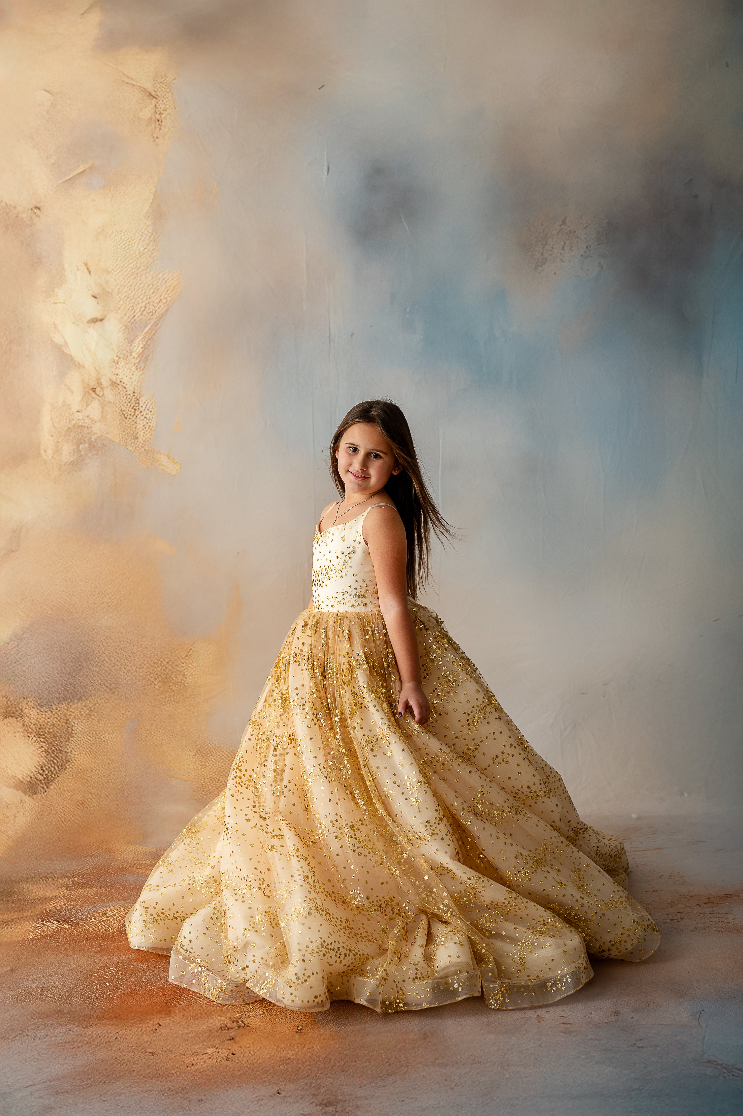 Girl gazing down in soft light wearing star-speckled gown