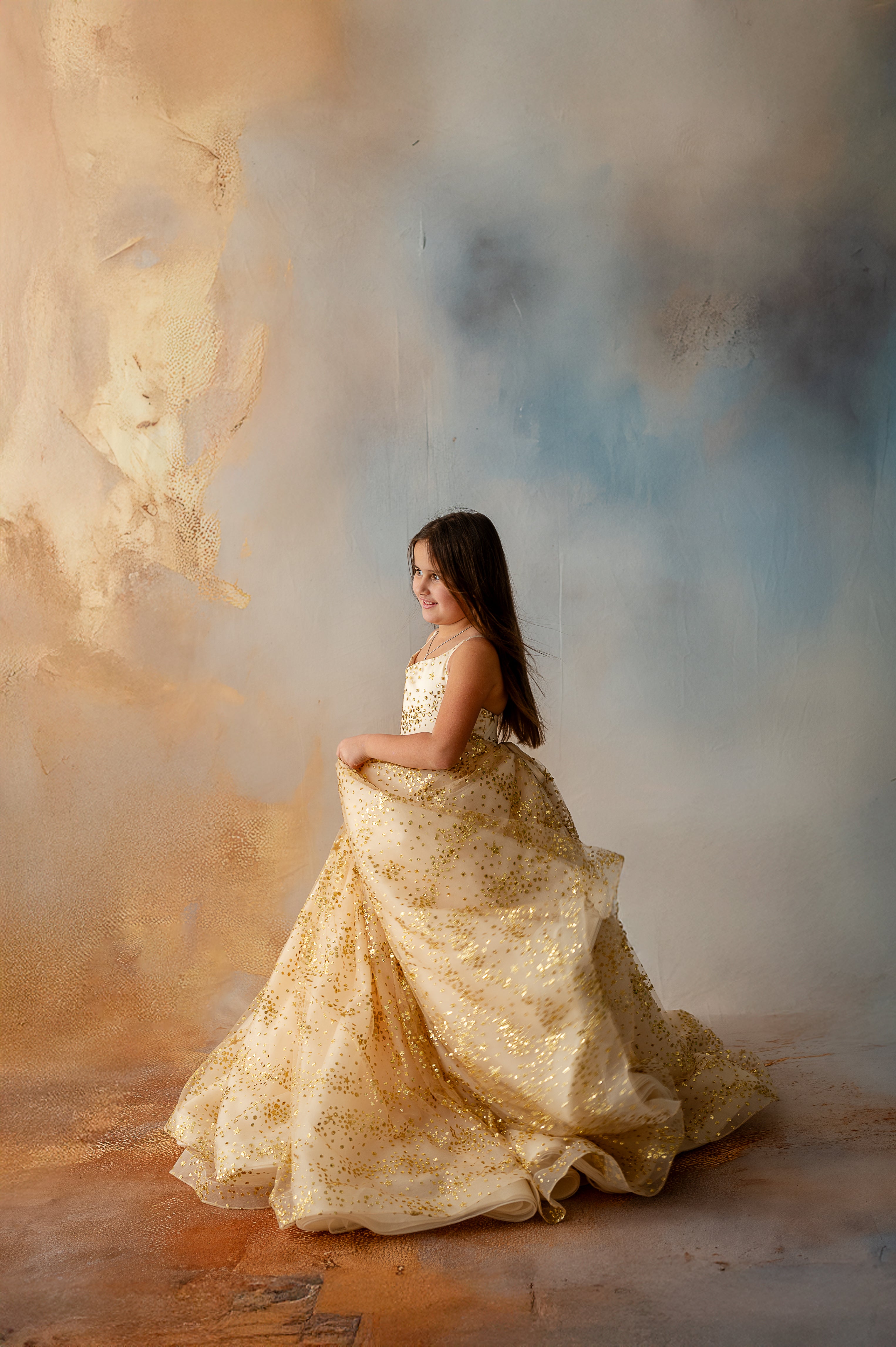 Girl sitting gracefully in gold star gown with full volume skirt