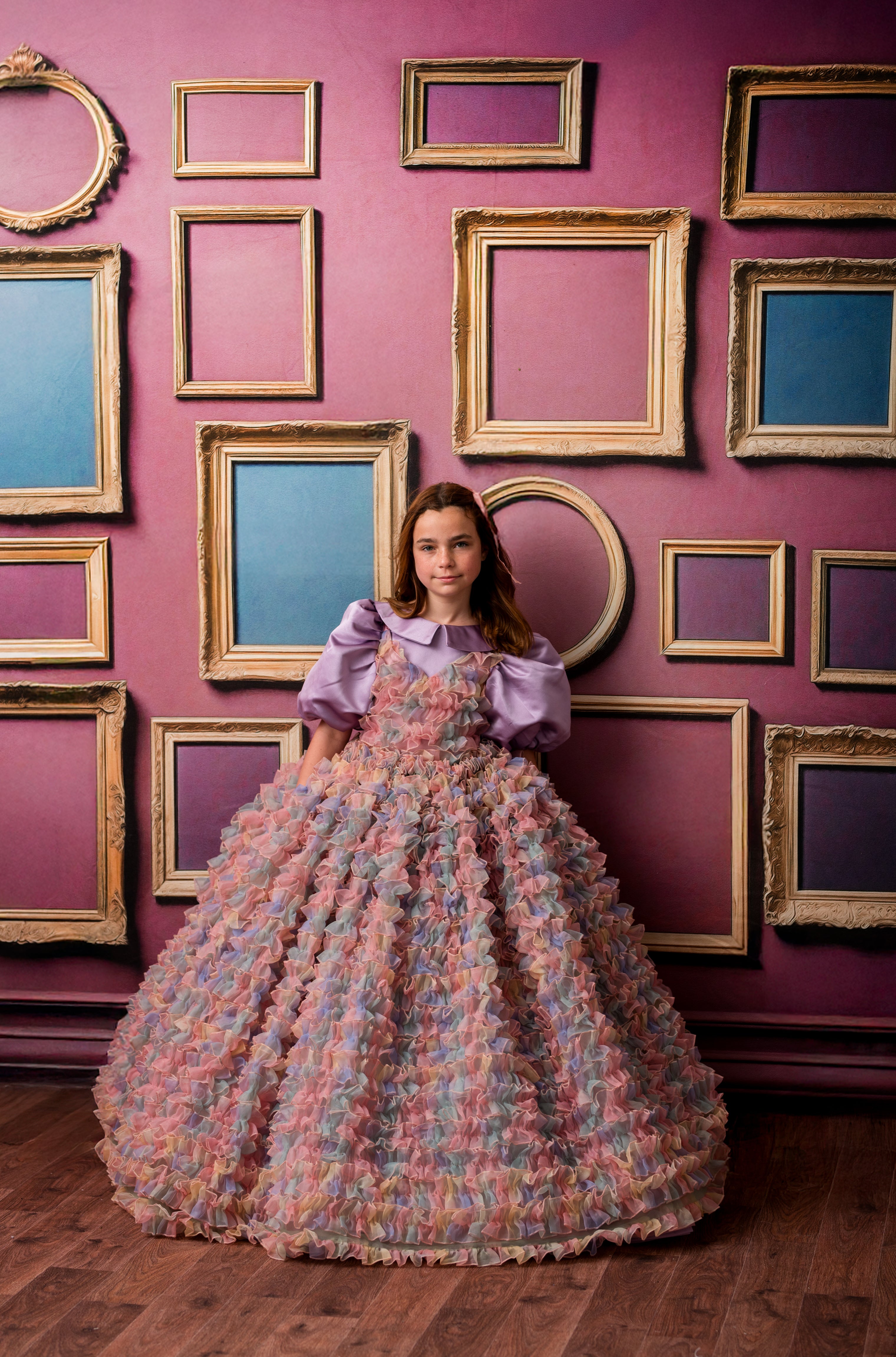 Woman in a floral dress standing in front of a wall with framed pictures.